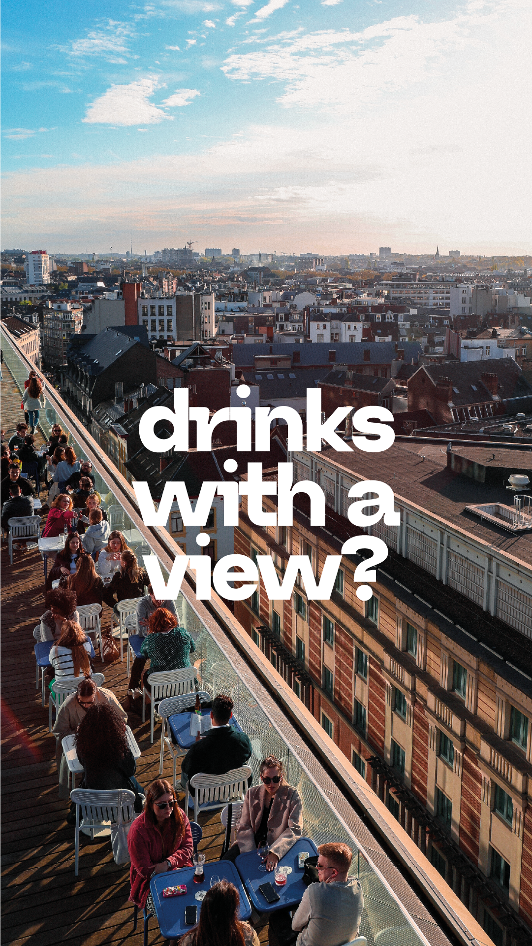 Une terrasse d'un toit avec des personnes assises à des tables, offrant une vue panoramique sur une ville urbaine avec des bâtiments de différentes hauteurs et un ciel partiellement nuageux.