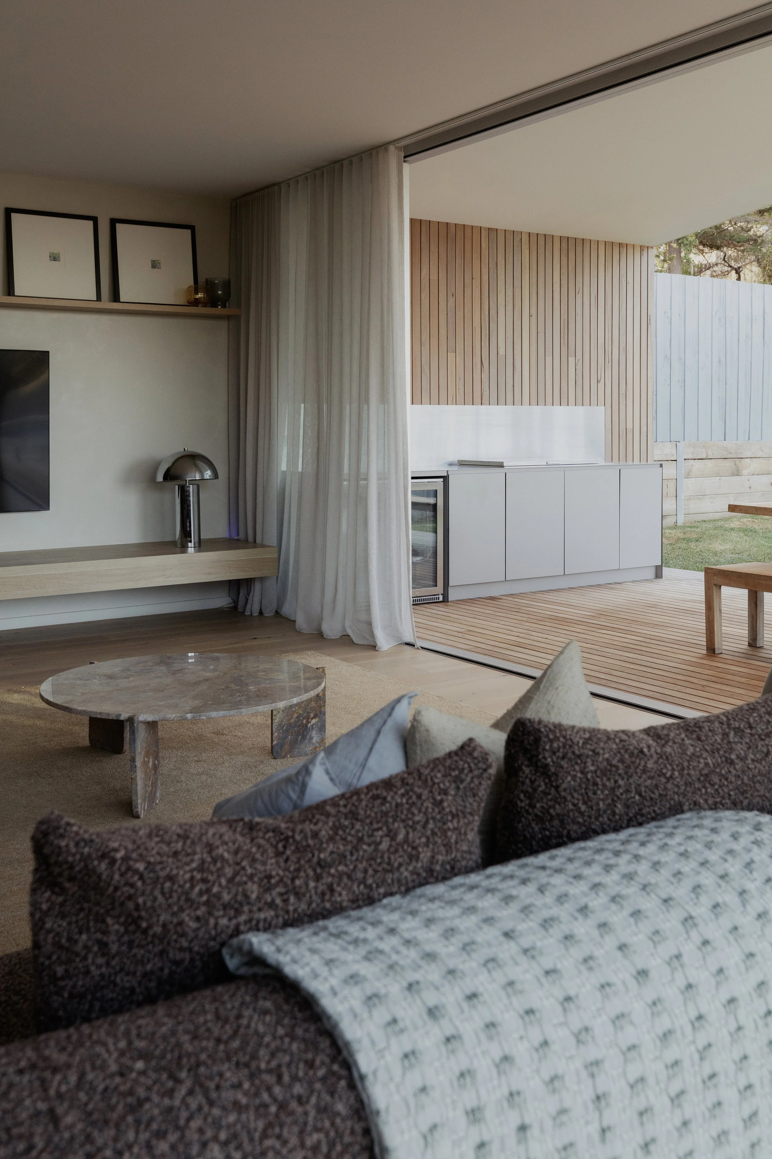 Build by Rawlinson, architecture by Pleaser Perkins. Seamless indoor outdoor living, silver chrome lamp, marble coffee table, boucle cushion, sheer curtains.