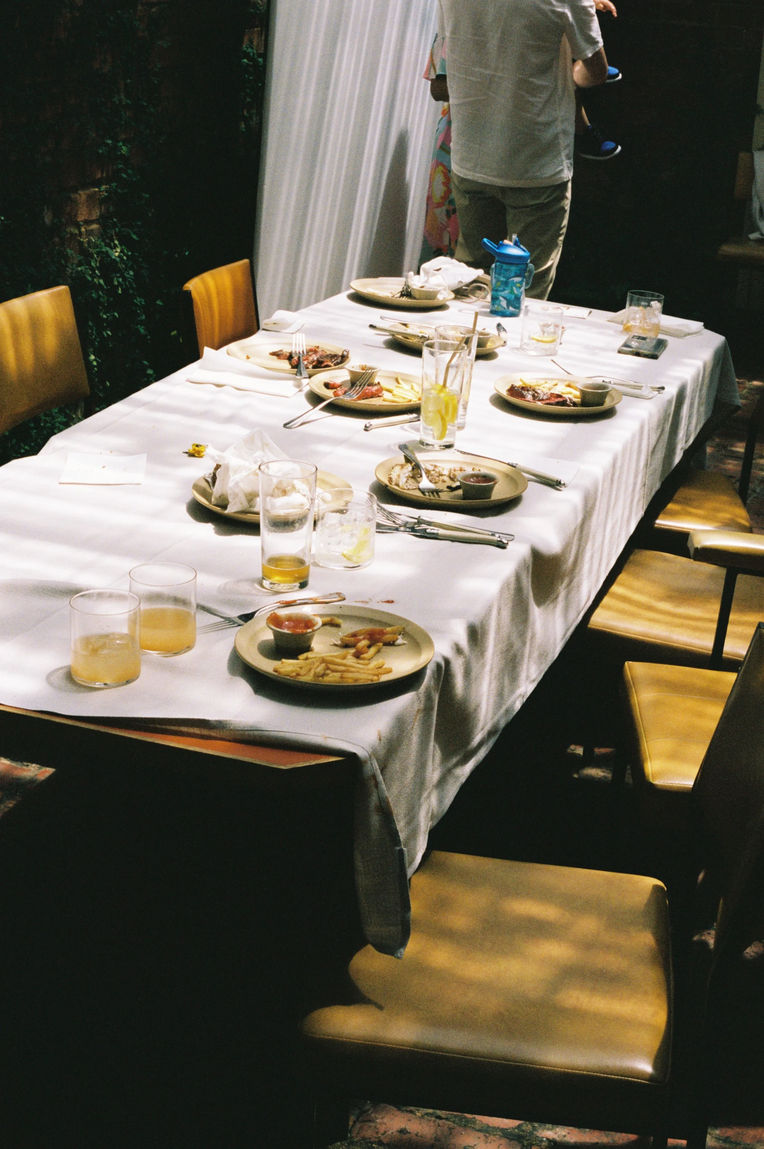 A dining table with leftover food and empty glasses, set for a meal in a restaurant or home setting with chairs around it.
