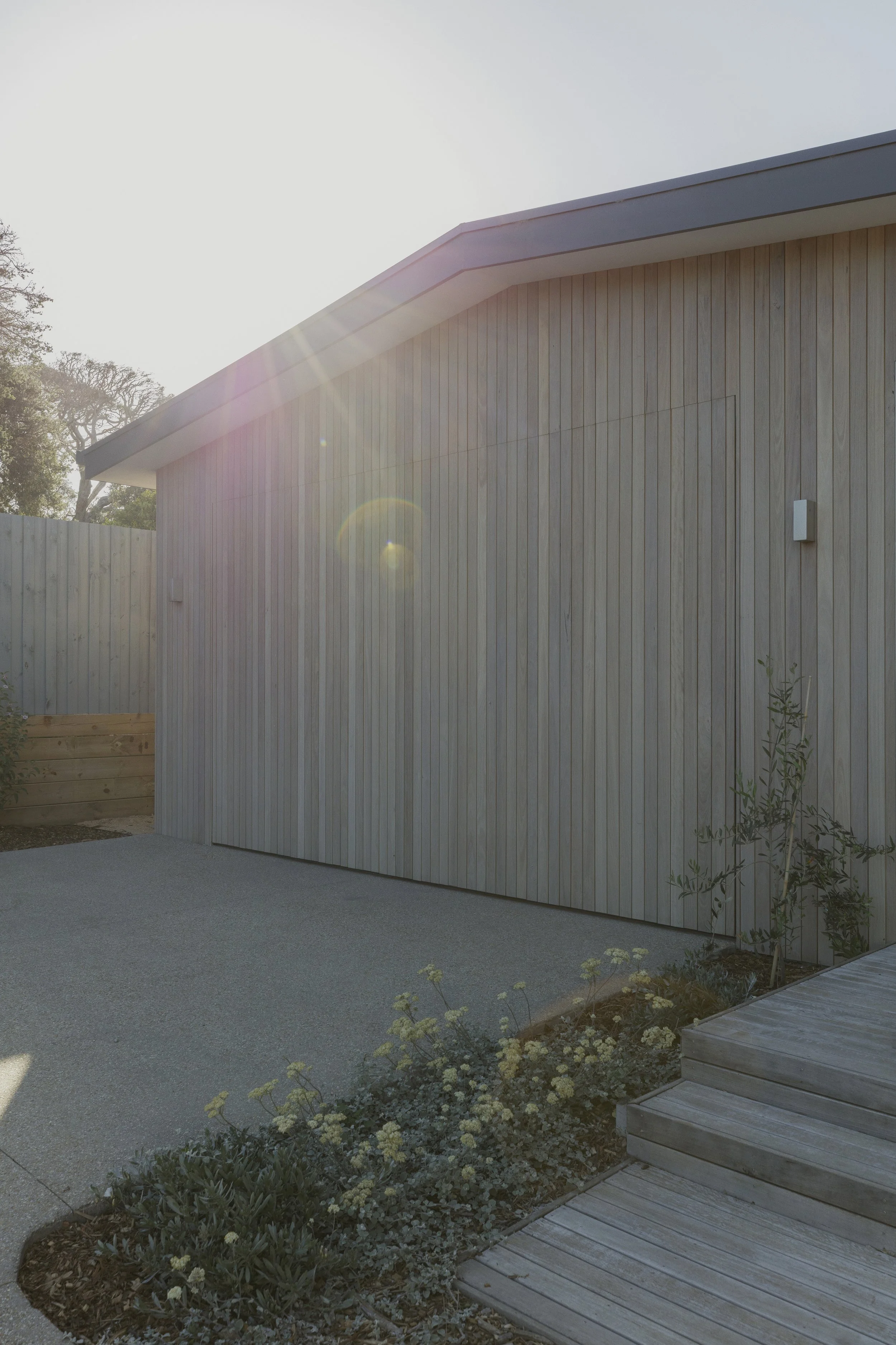 Build by Rawlinson, architecture by Pleaser Perkins. Sun flare over timber coastal building facade