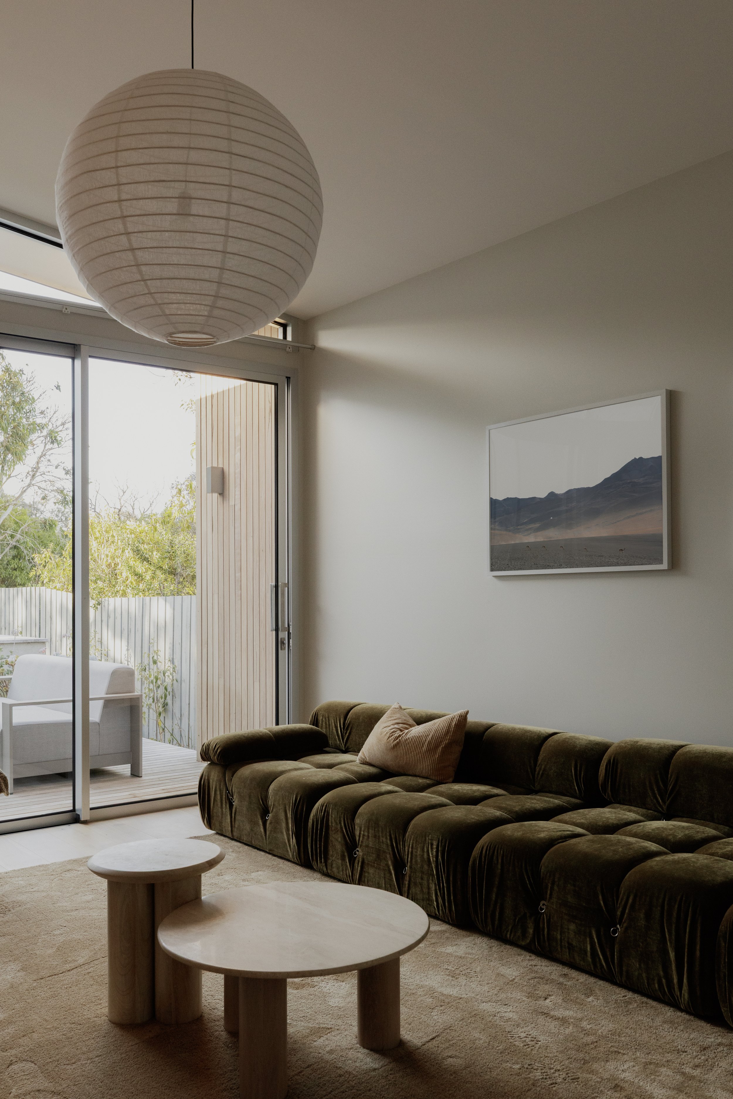 Build by Rawlinson, architecture by Pleaser Perkins. Lounge area modern architectural home, sunken lounge, green couch, marble table, paper lantern, desert artwork, tan rug.