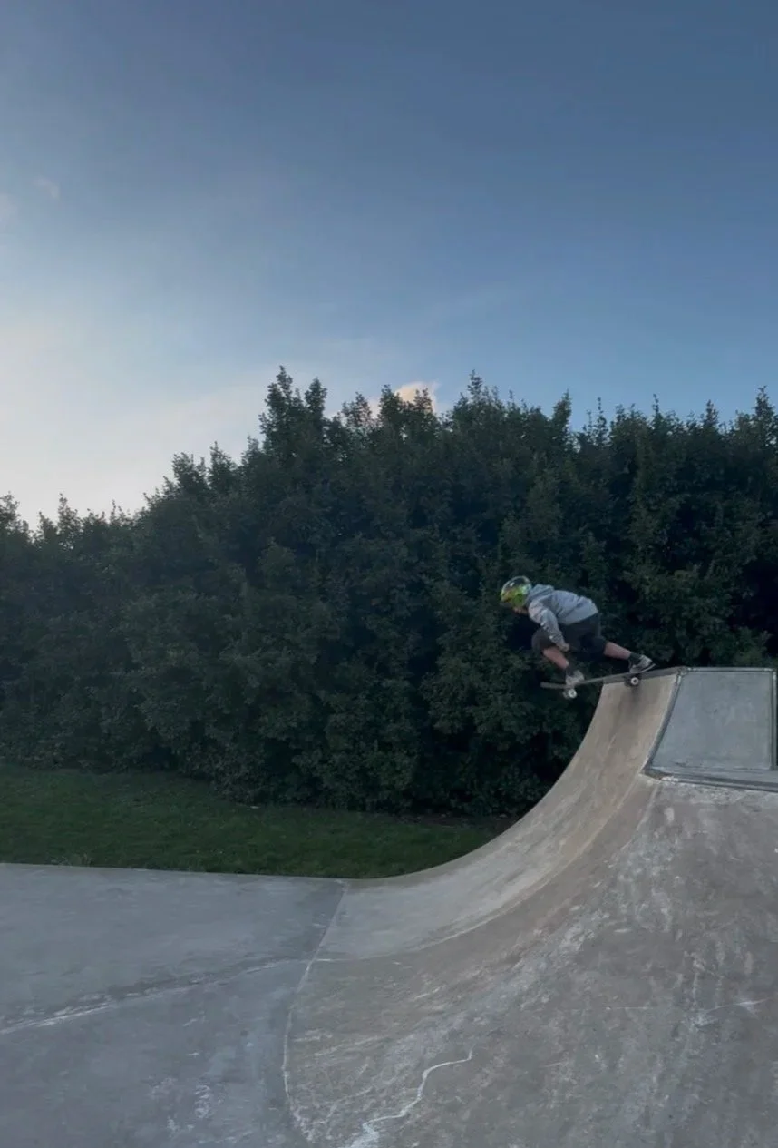 A person wearing a helmet riding a skateboard on a ramp at a skate park during the evening.