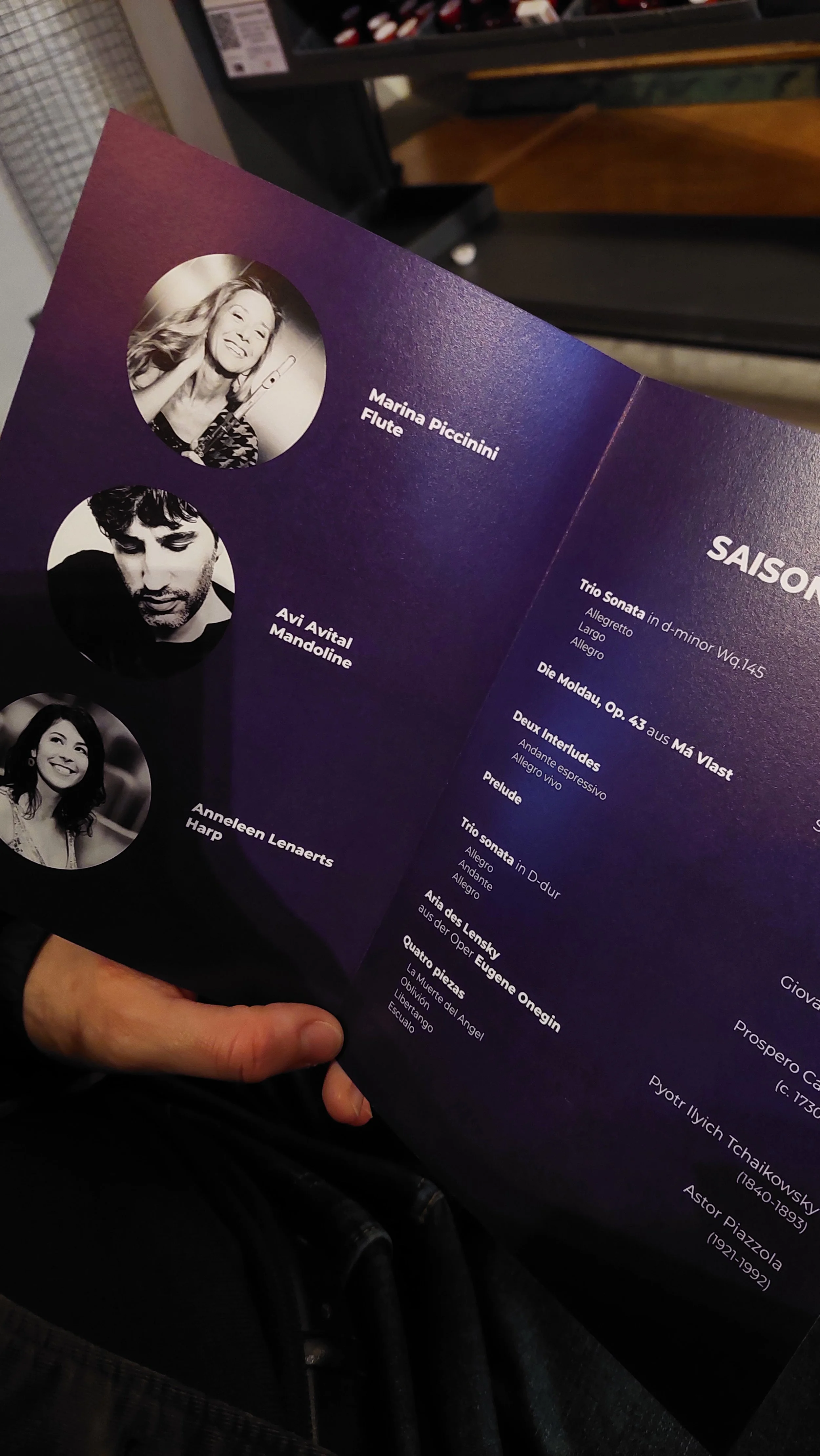 A concert program featuring three musicians: Marina Piccinini with a flute, Avi Avital with a mandolin, and Anneleen Lenaerts with a harp. The program lists various classical music pieces and their composers.