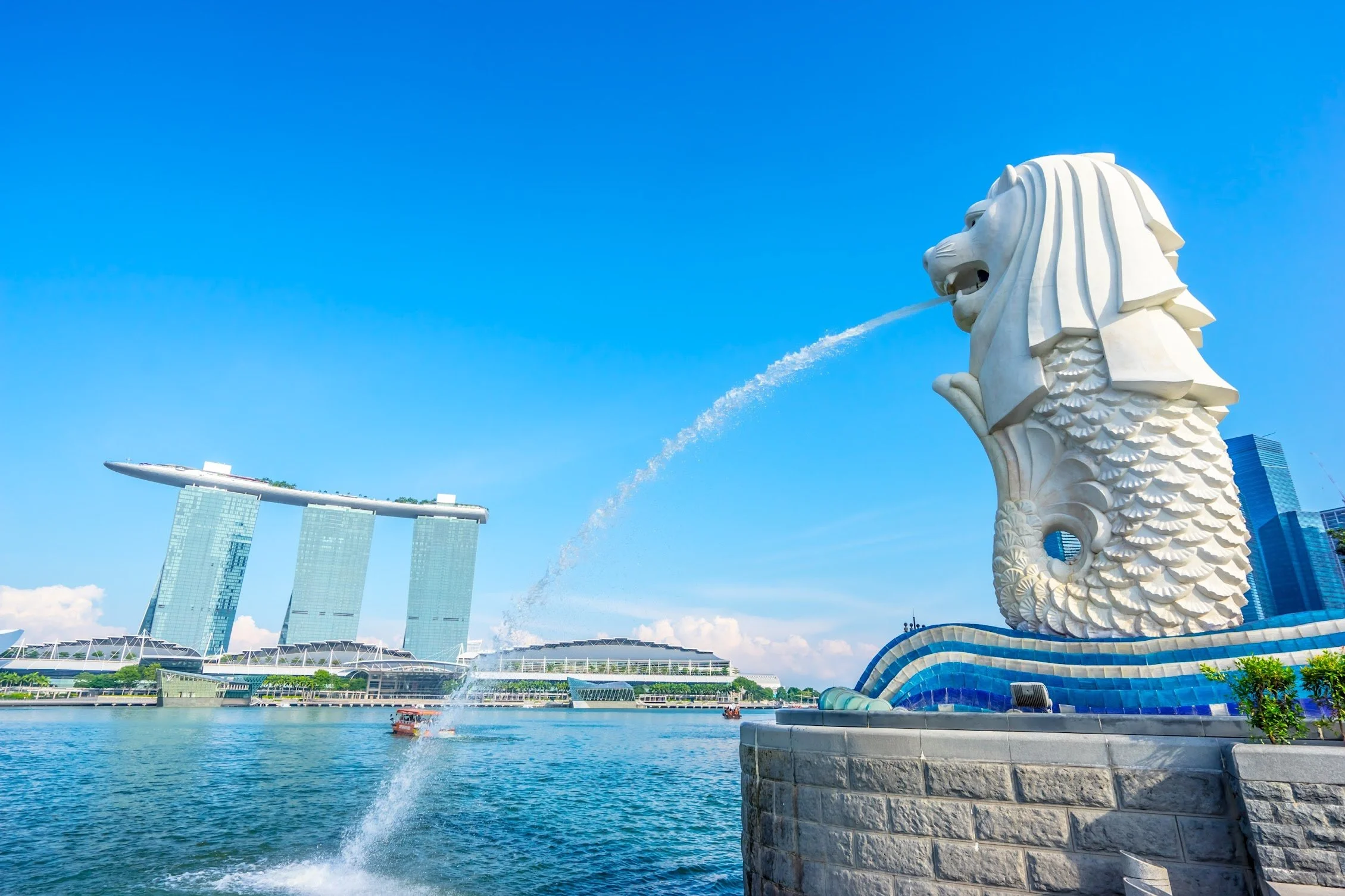The Merlion statue spouting water at Merlion Park in Singapore with Marina Bay Sands and the waterfront skyline in the background