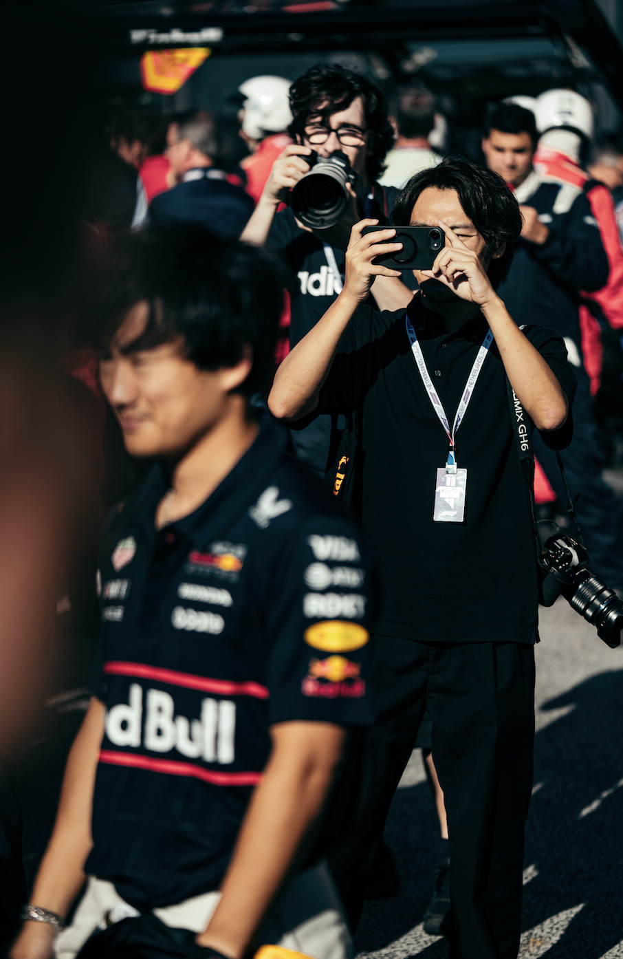 A Formula 1 fan taking a photo of driver Yuki Tsunoda during a Grand Prix race weekend