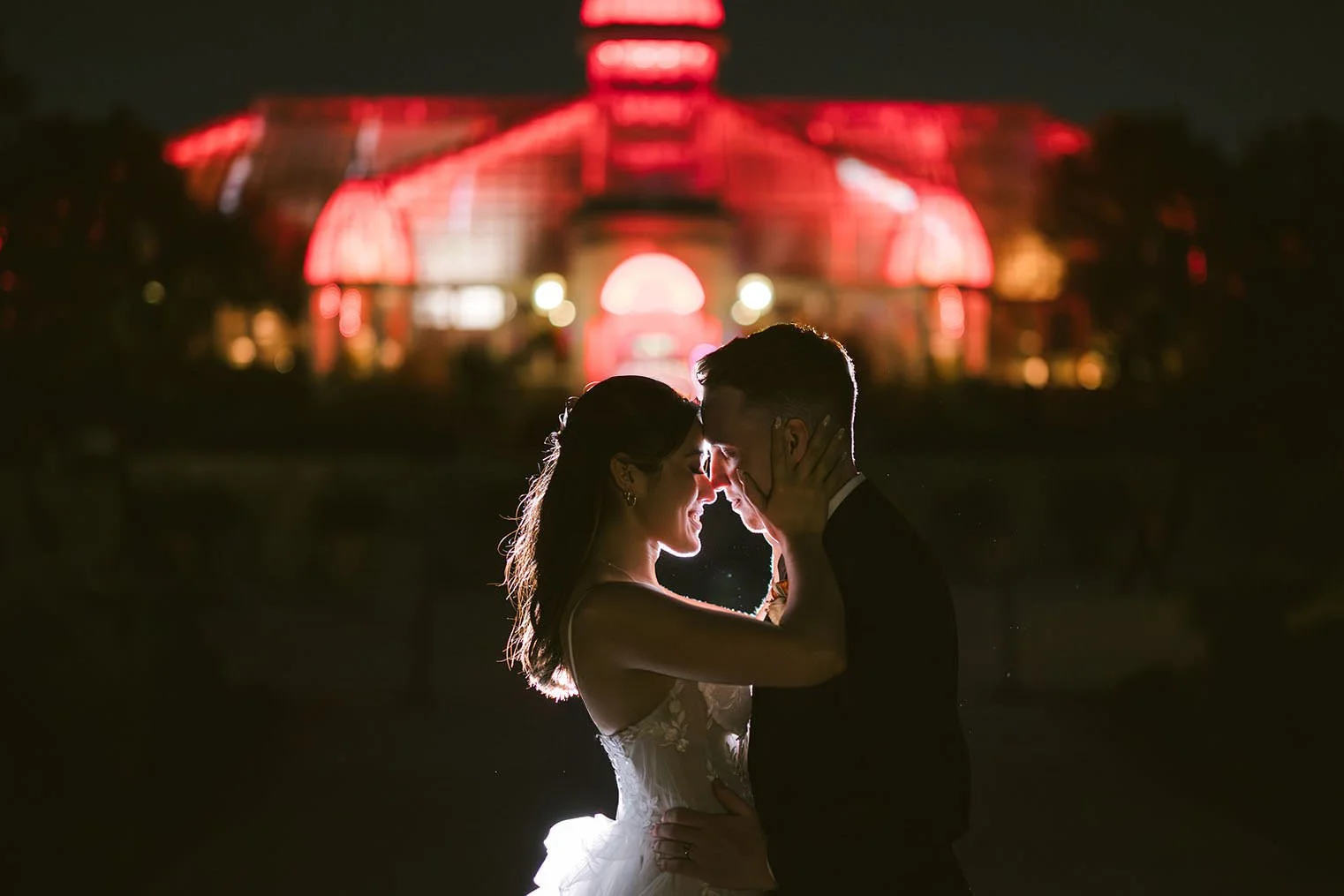 Bride and Groom sharing a moment lit up at night with the Franklin Park Conservatory colorful in the background.