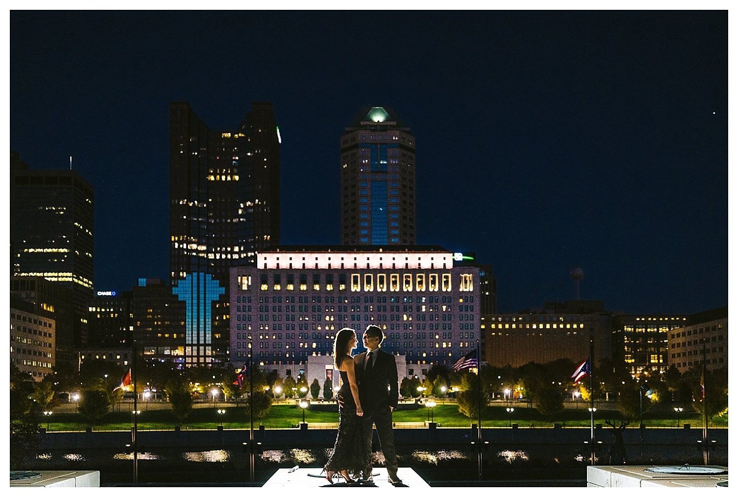 Night city scape engagement photo of a couple in Columbus Ohio along the Scioto Mile at North Bank Pavilion 