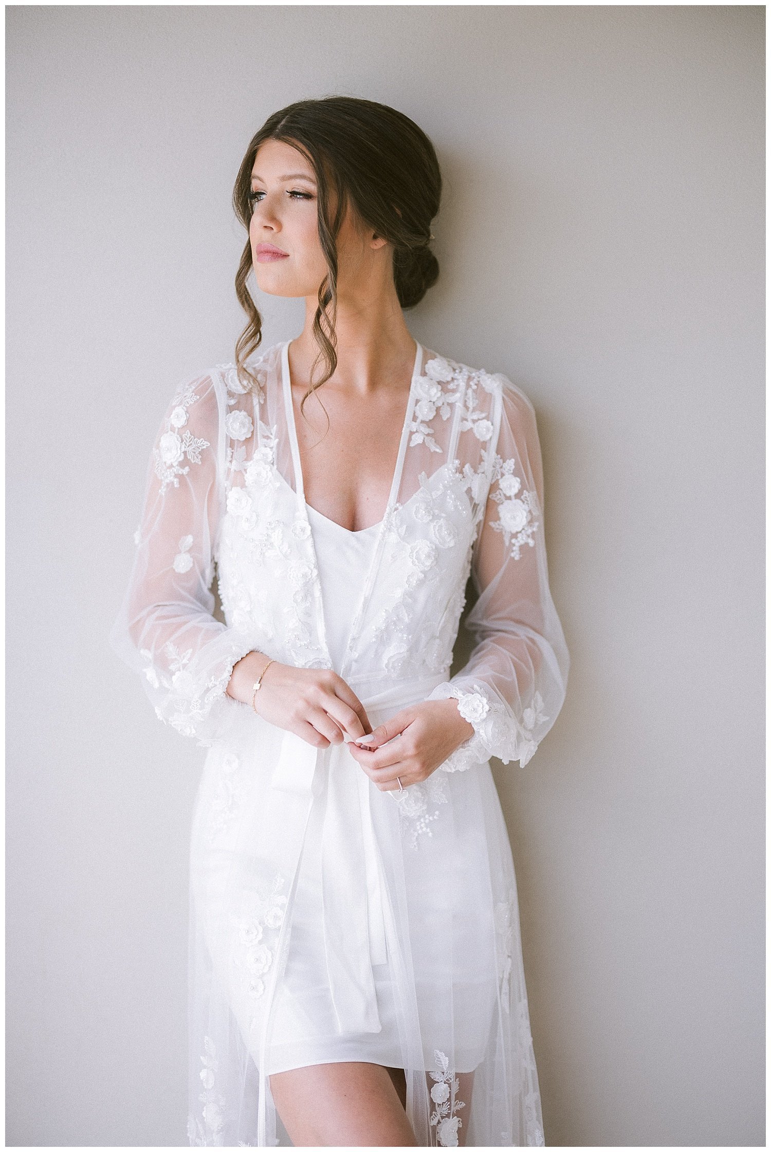 a bride in a white lace robe posing for wedding photos
