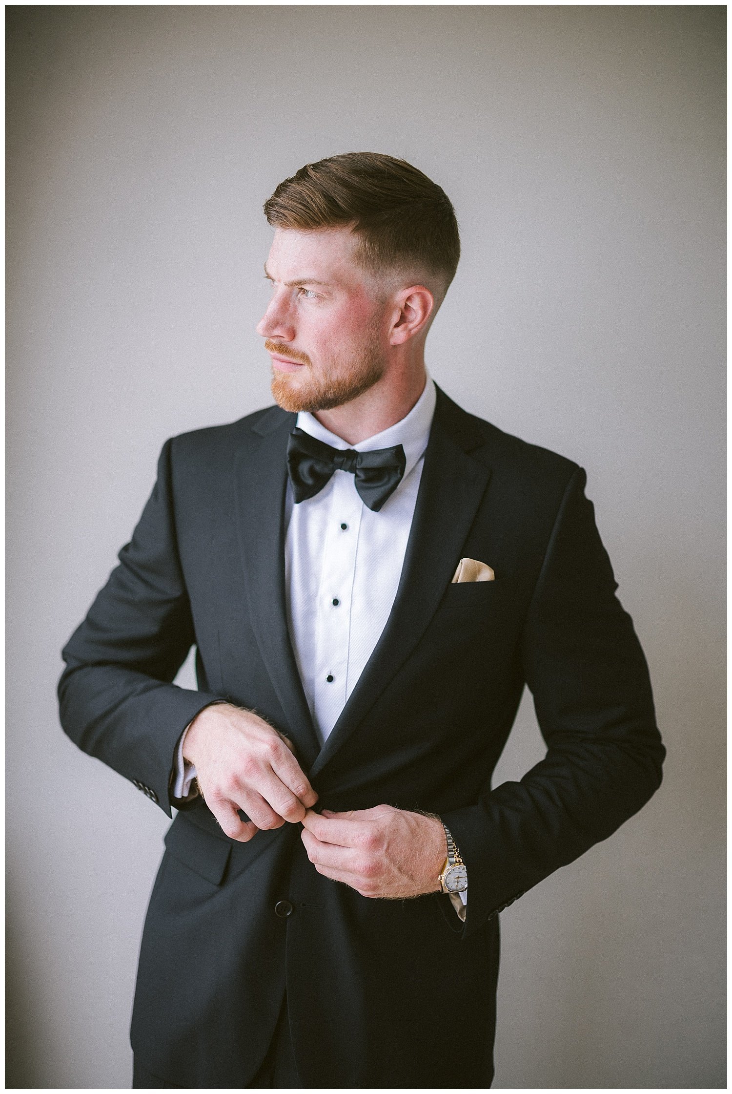 closeup photo of a groom buttoning his suit jacket