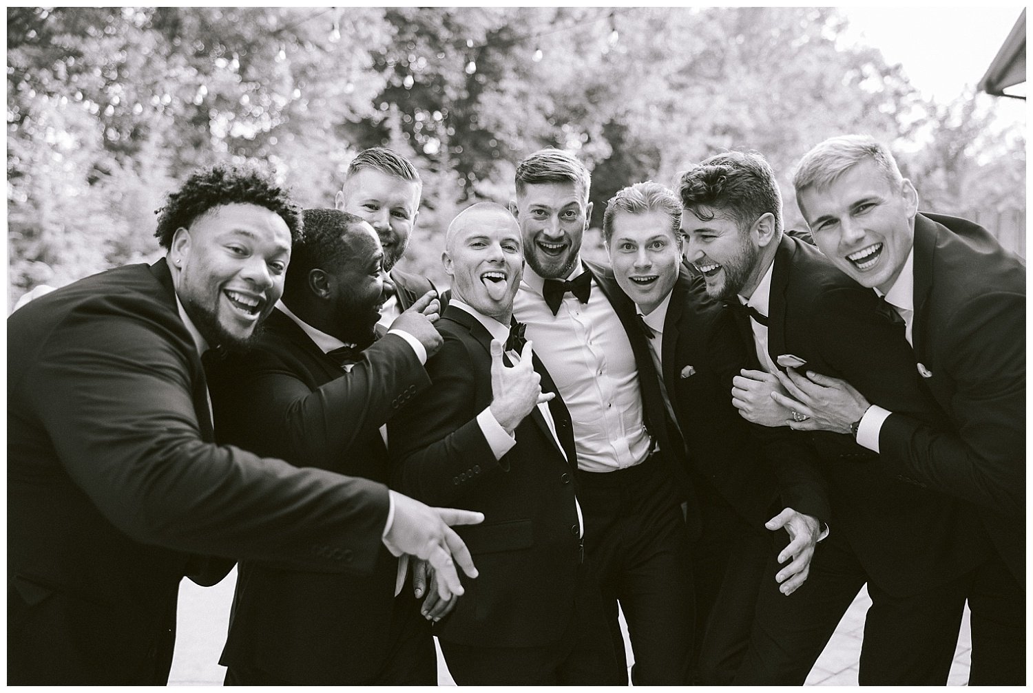 A photo of a groom and groomsmen hugging.