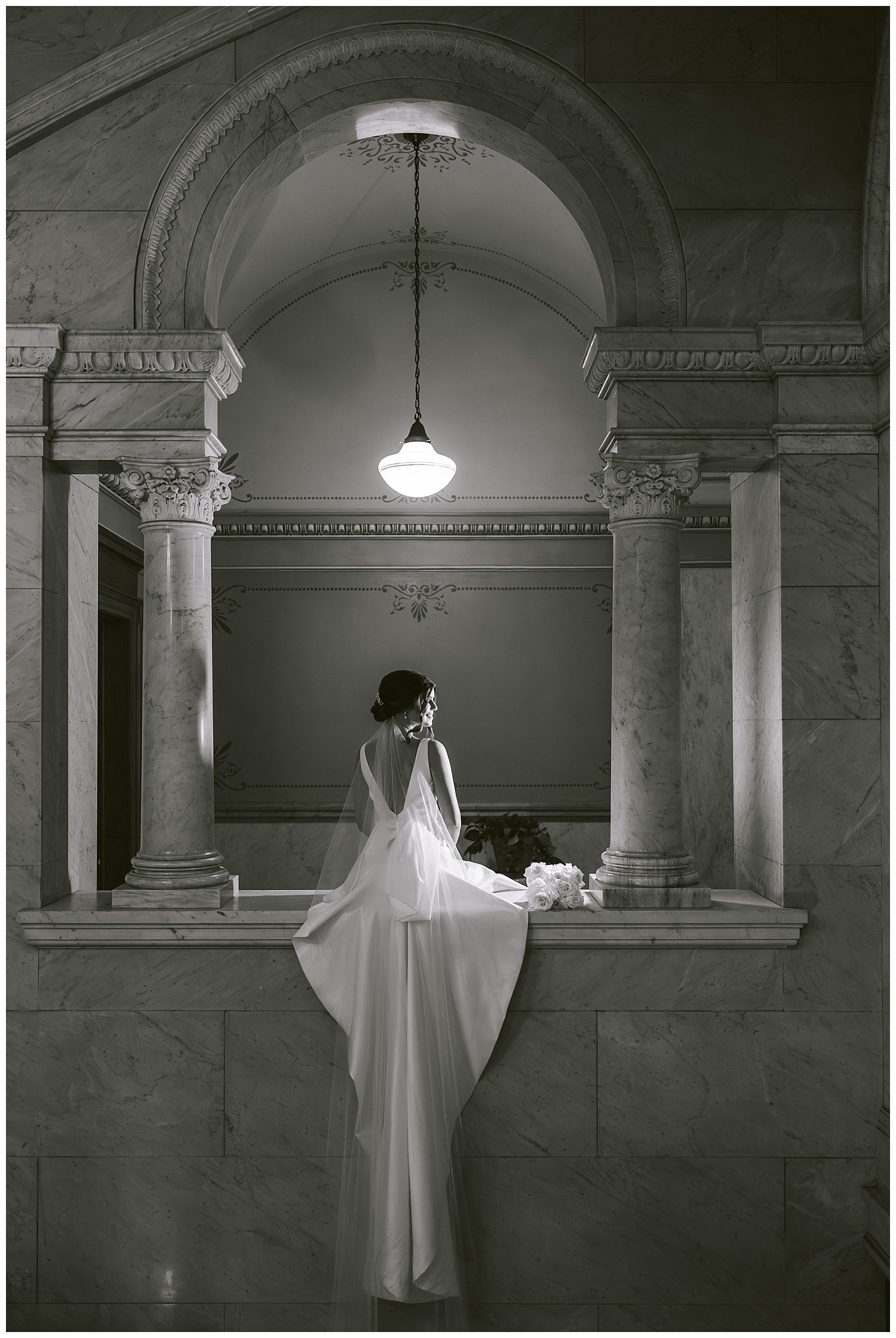 Black and white photo of a bride in dramatic lighting posing for wedding photos at the Ohio Statehouse