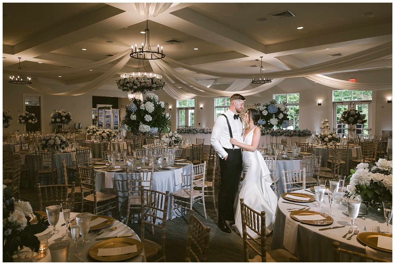 A wedding couple posing in a beautifully decorated room with white florals and details at the Estate wedding venue in New Albany, Ohio. 
