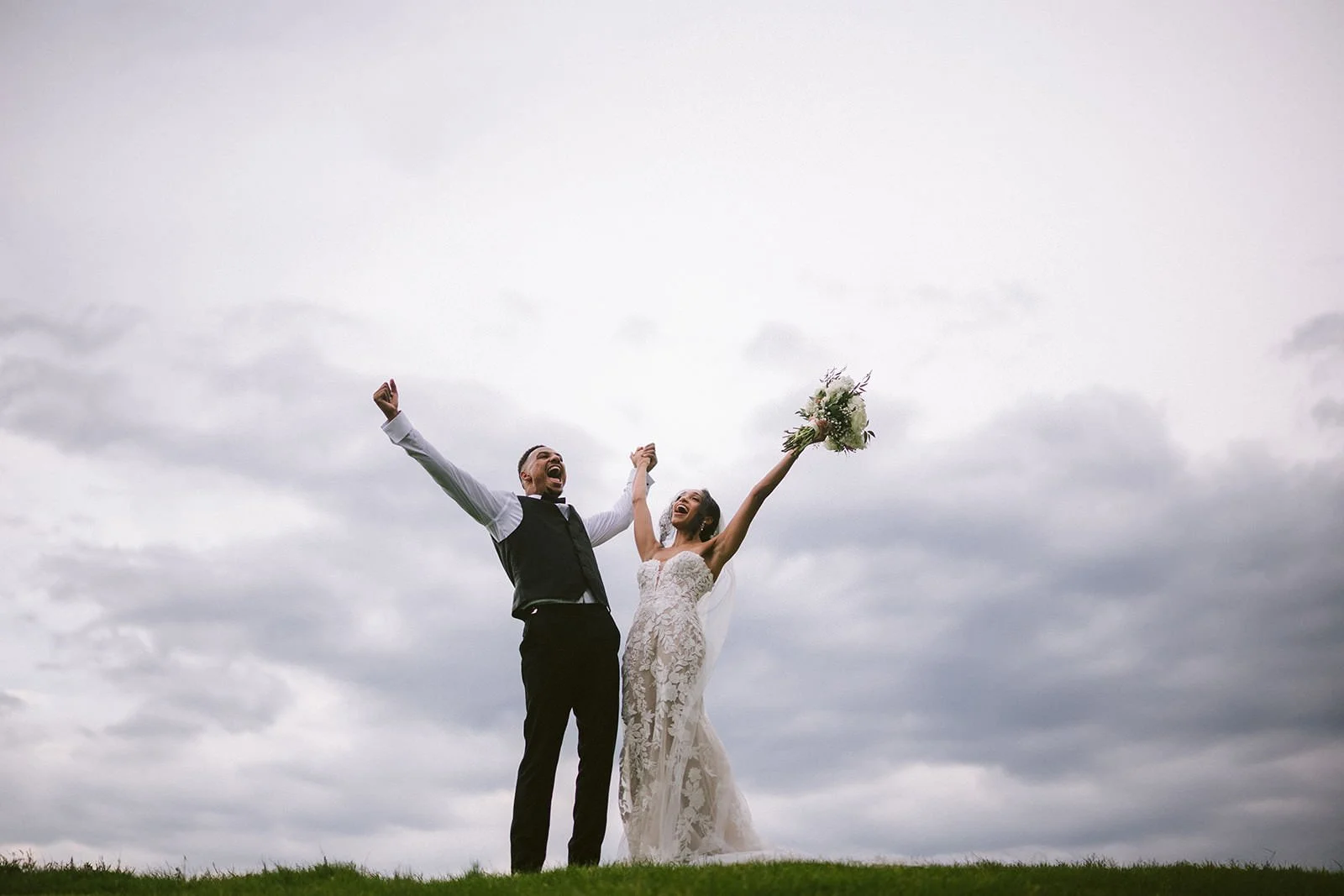 Bride and Groom sharing a moment of joy in a cloud filled sky.