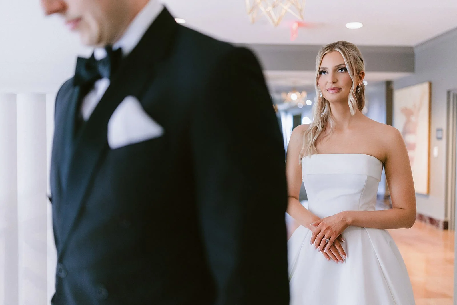 A bride with her groom in the foreground during a first look.