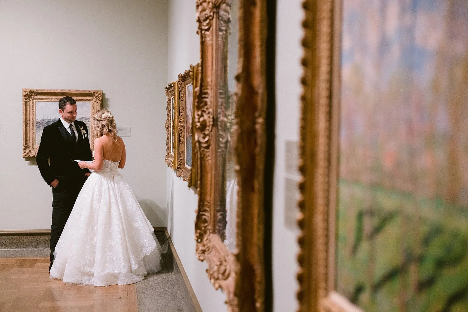 Bride and groom reading their vows beside gold-framed paintings in a Columbus Museum of Art gallery