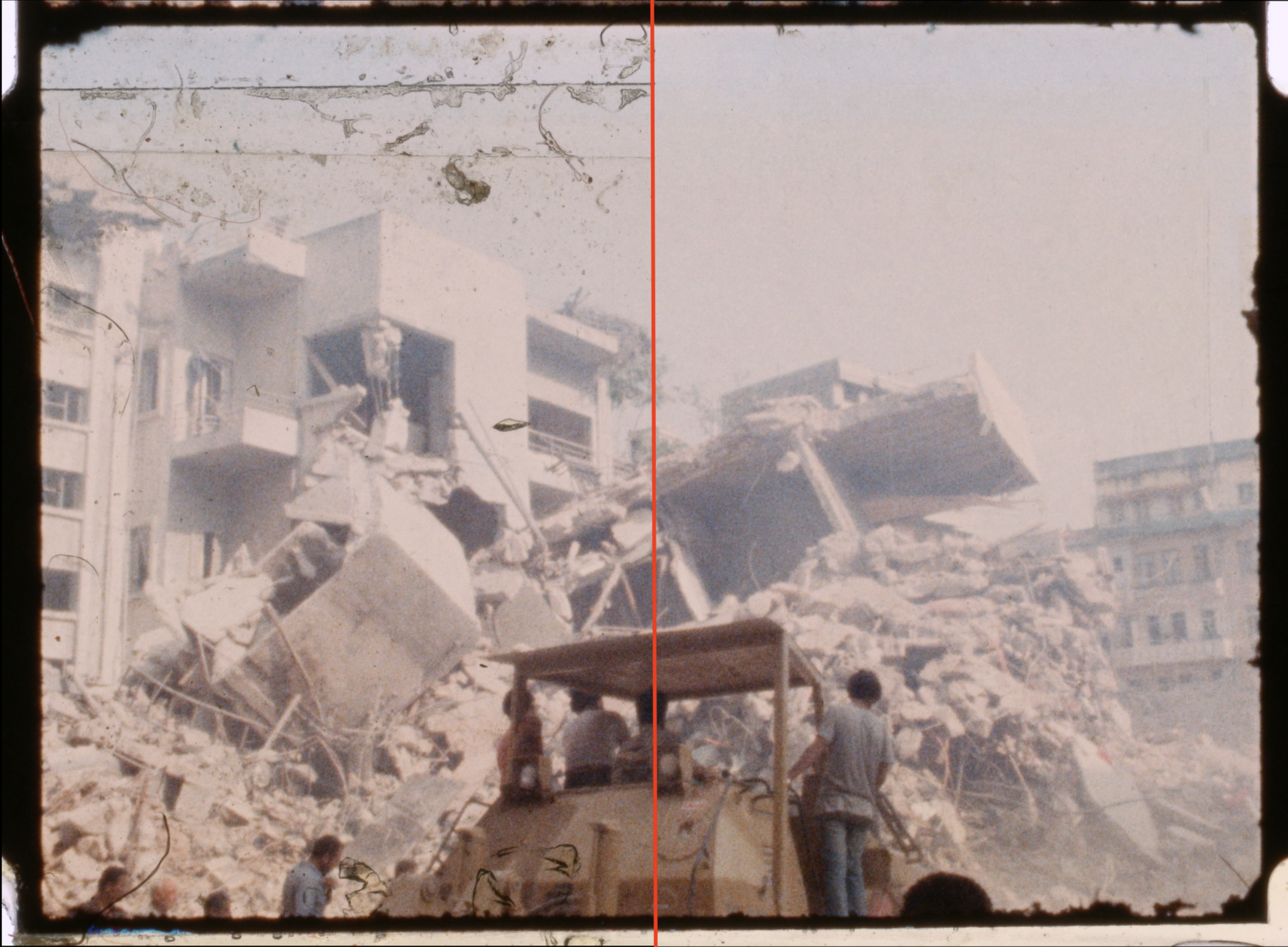 Black and white photograph of a building collapse with rubble and debris, and several people and construction machinery in the foreground.