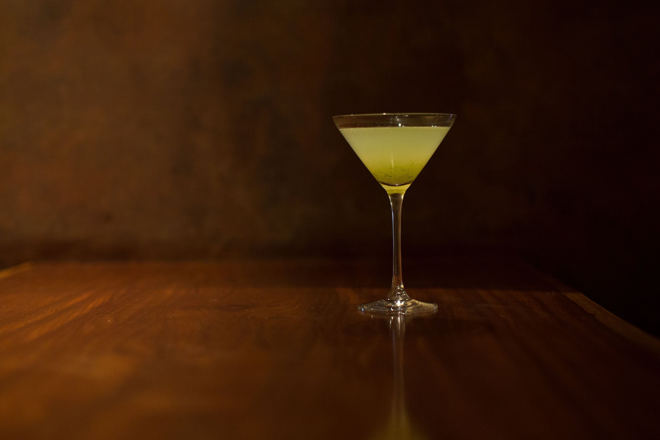  A single green cocktail in a martini glass. 