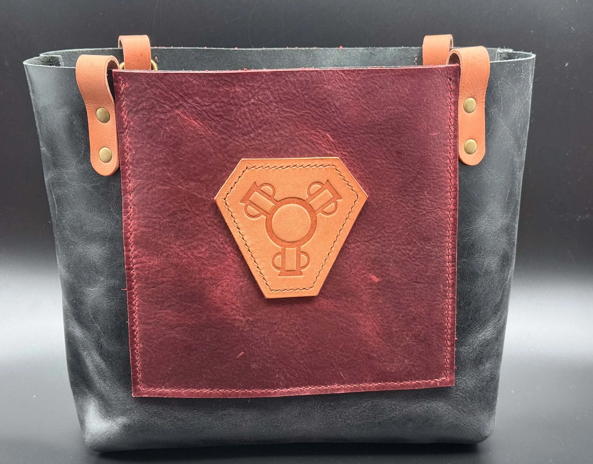 medium tote bag, 3 pots badge, black vegtan matt finish , 10"h x 10"w x 5"d, black cherry oil tanned leather front and back pockets 7"h x 7"w