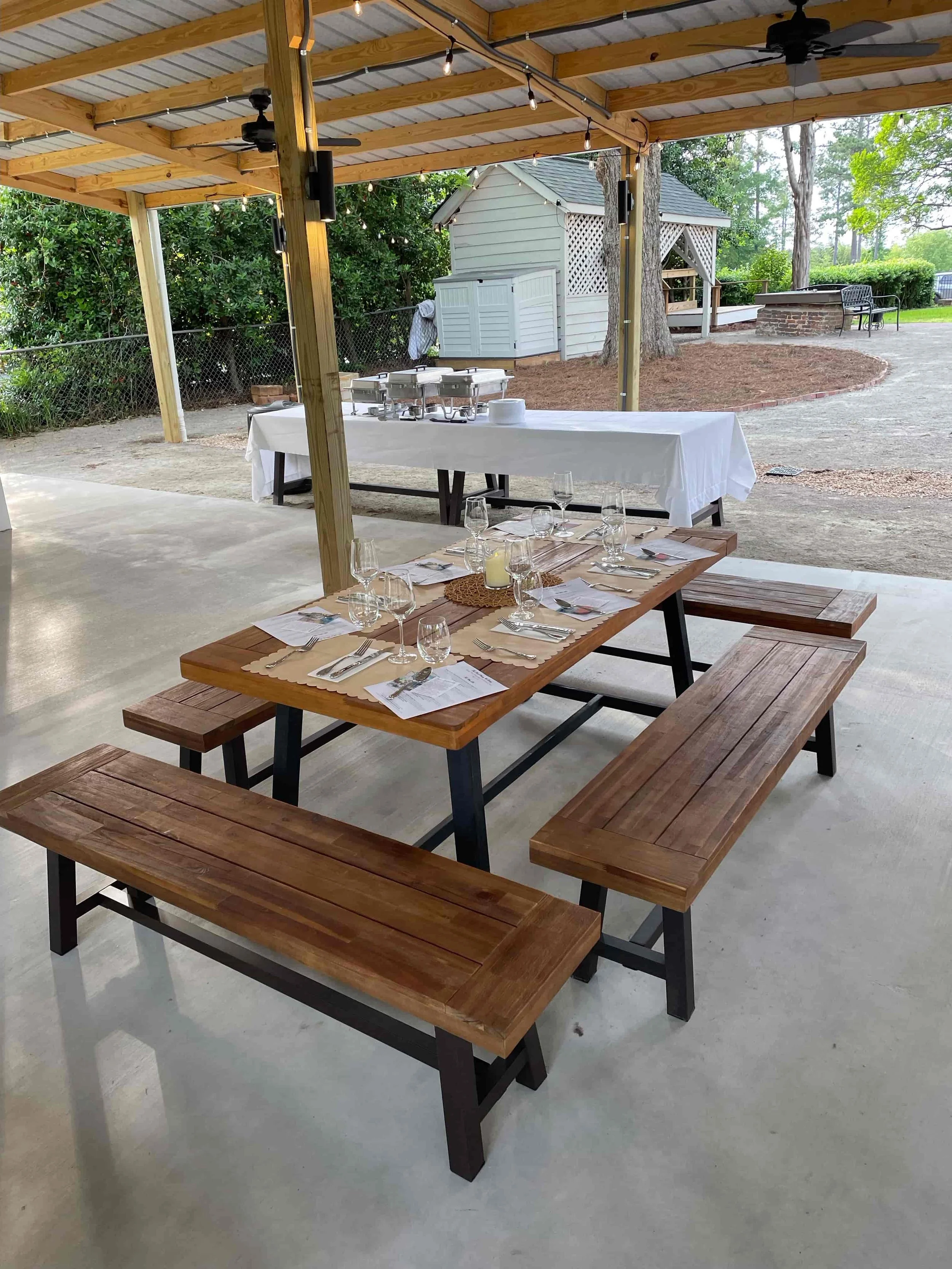 Picnic table setup under the open-air pavilion at The Boland House prepared for an event
