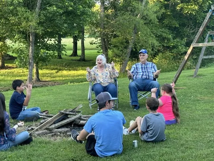Mrs. Betty and Bro. Kelley leading worship with youth around bonfire.