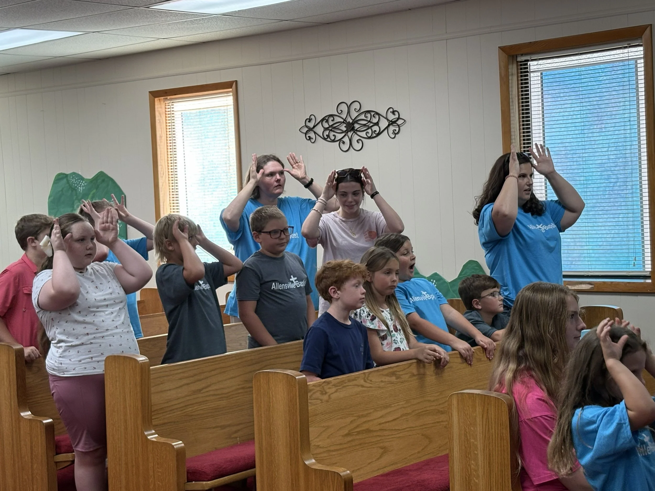 A group of children and two women participating in music session at Vacation Bible School.
