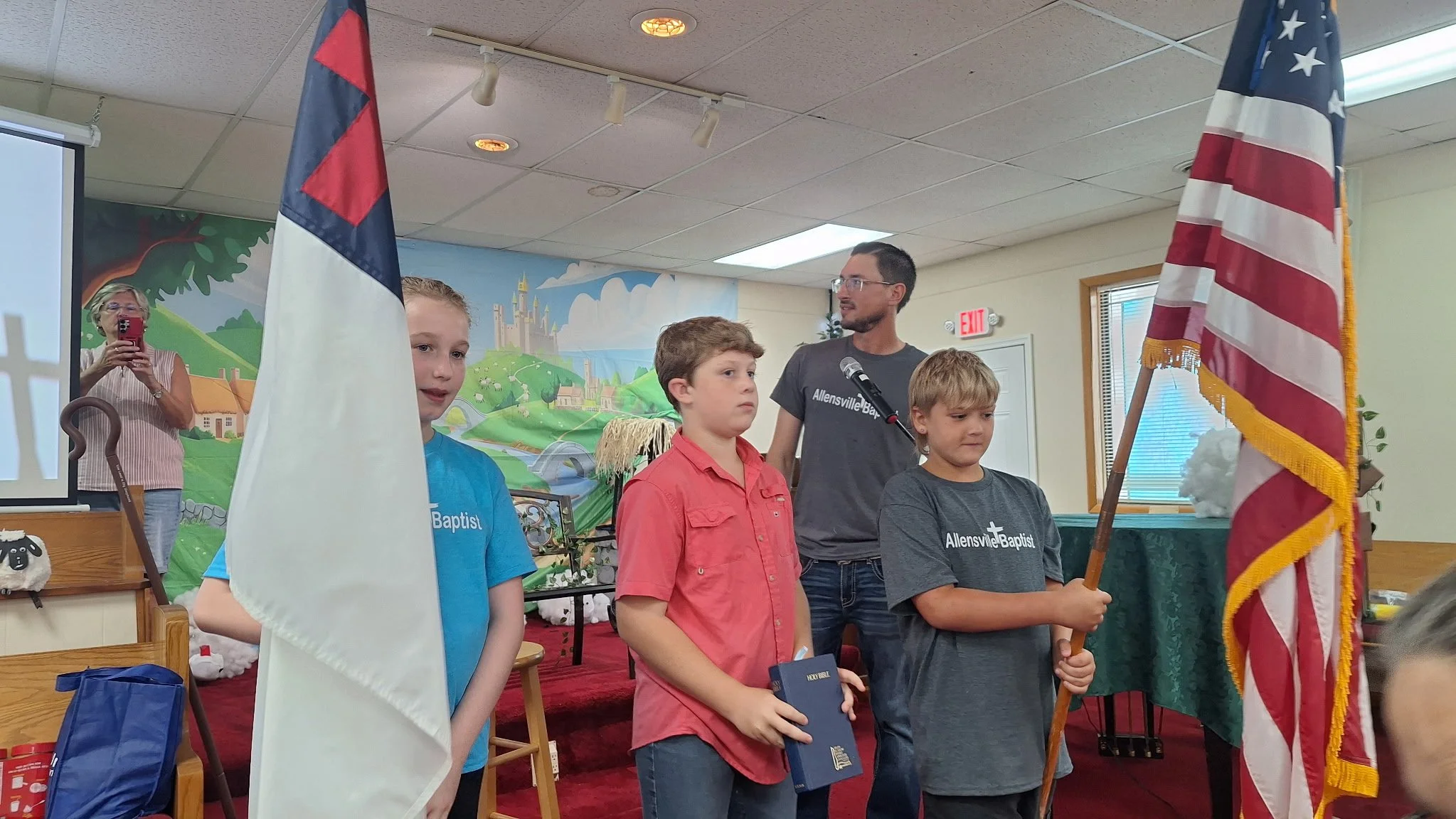 Church youth hold the Christian flag, Holy Bible and American flag during Vacation Bible School.