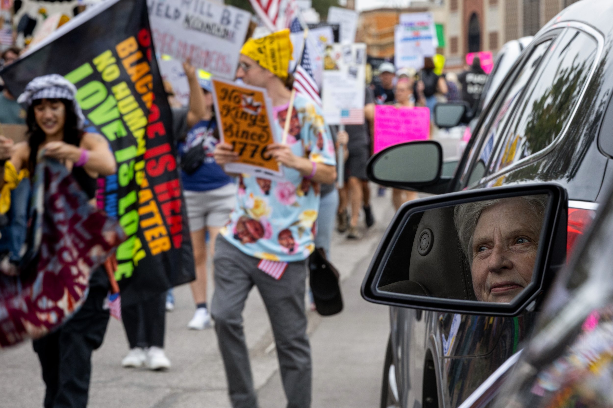 Jane Stotts watches from her car with an approving smile as thousands march by during the No Kings protest on Oct. 18, 2025, in Kansas City, Mo.