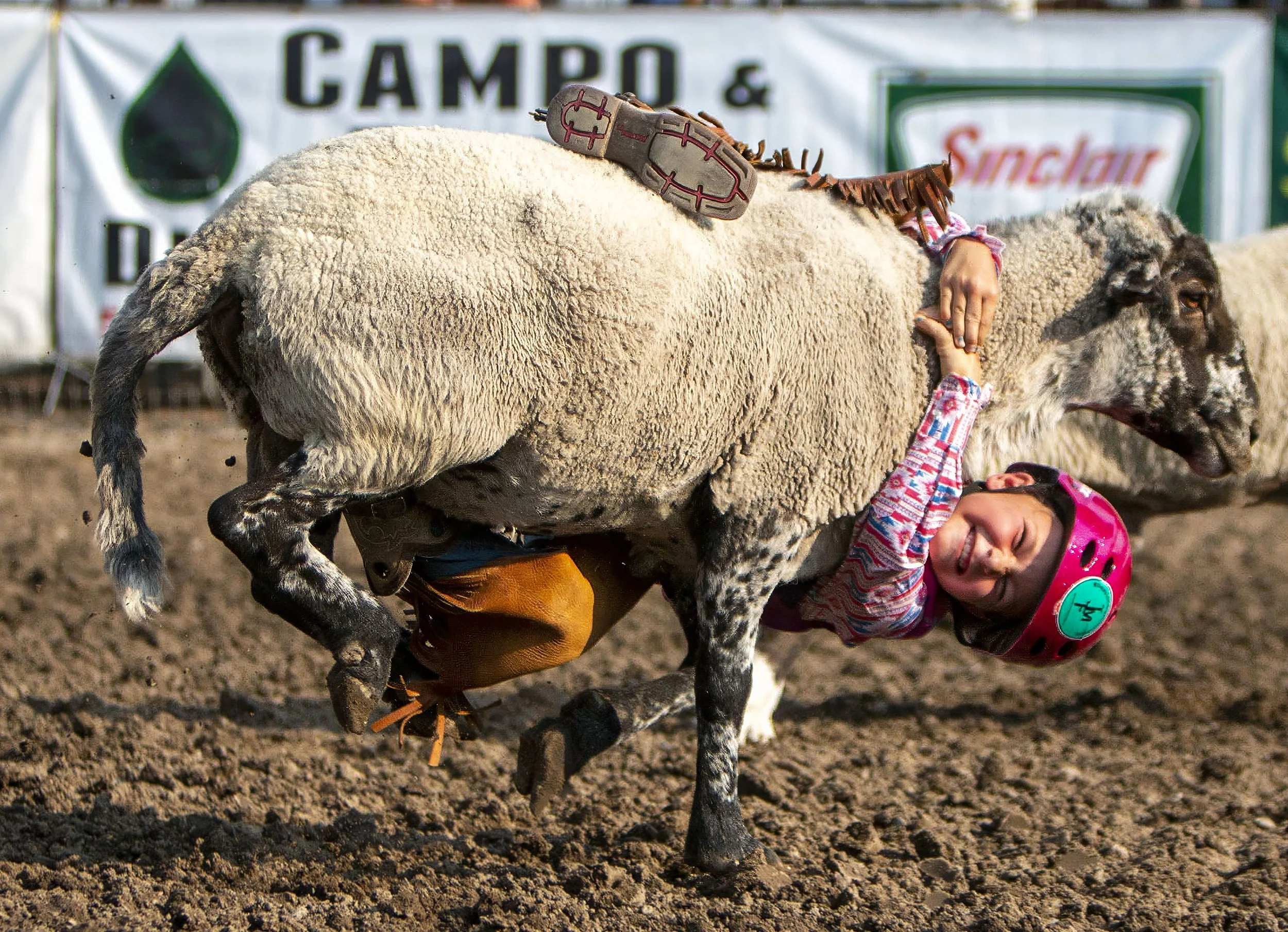 Avery Randall smiles as she holds fast to the neck of a sheep during the mutton bustin’ event at the Vale 4th of July Rodeo on July 3, 2021, in Vale. Ore.