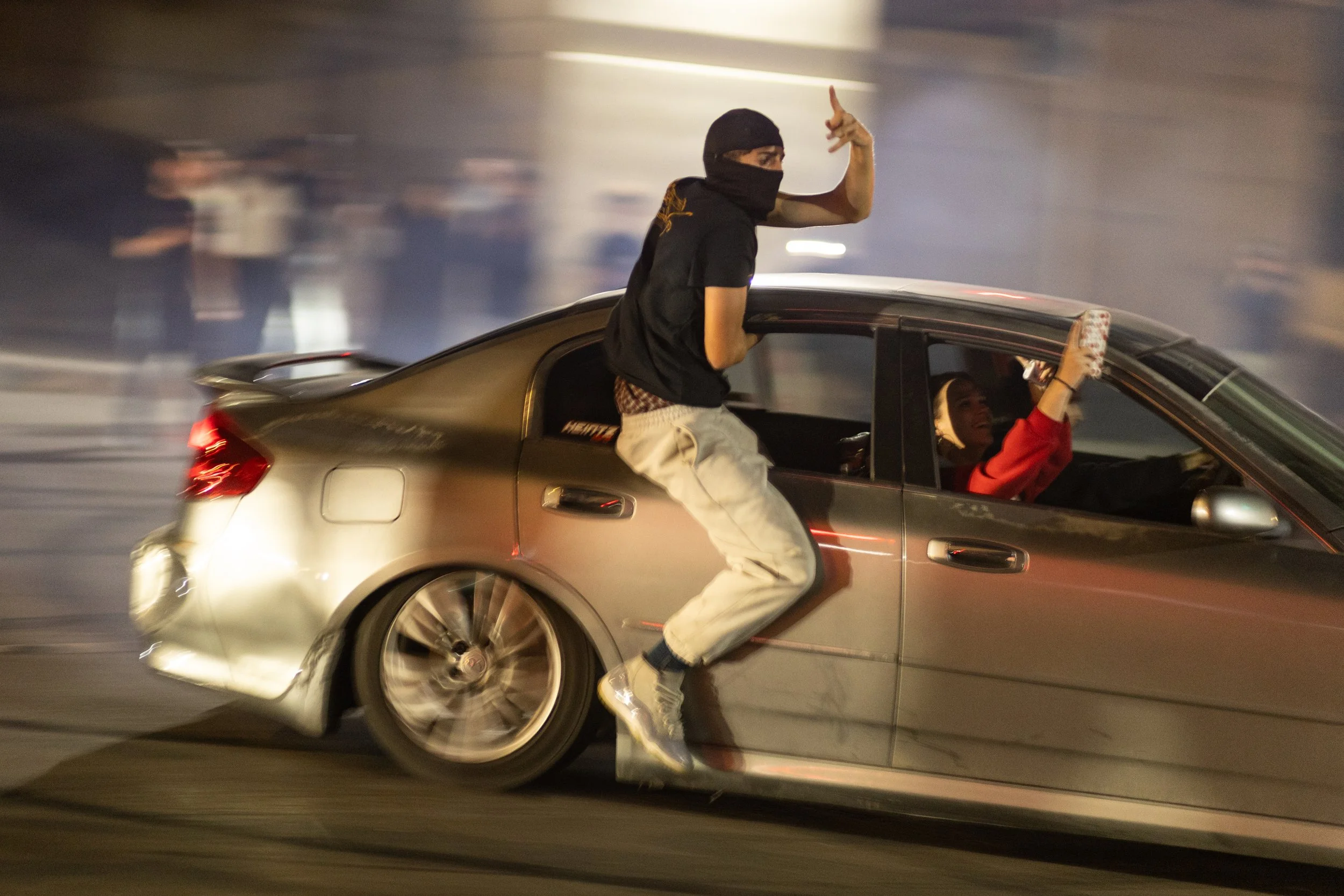 An individual hangs halfway out the window of a drifting car during an illegal slideshow takeover on Sept. 20, 2025, in Kansas City, Mo. 