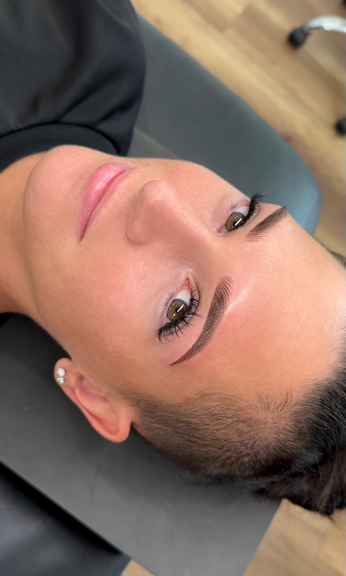 Close-up of woman lying on a table, showing freshly shaped and filled eyebrows.