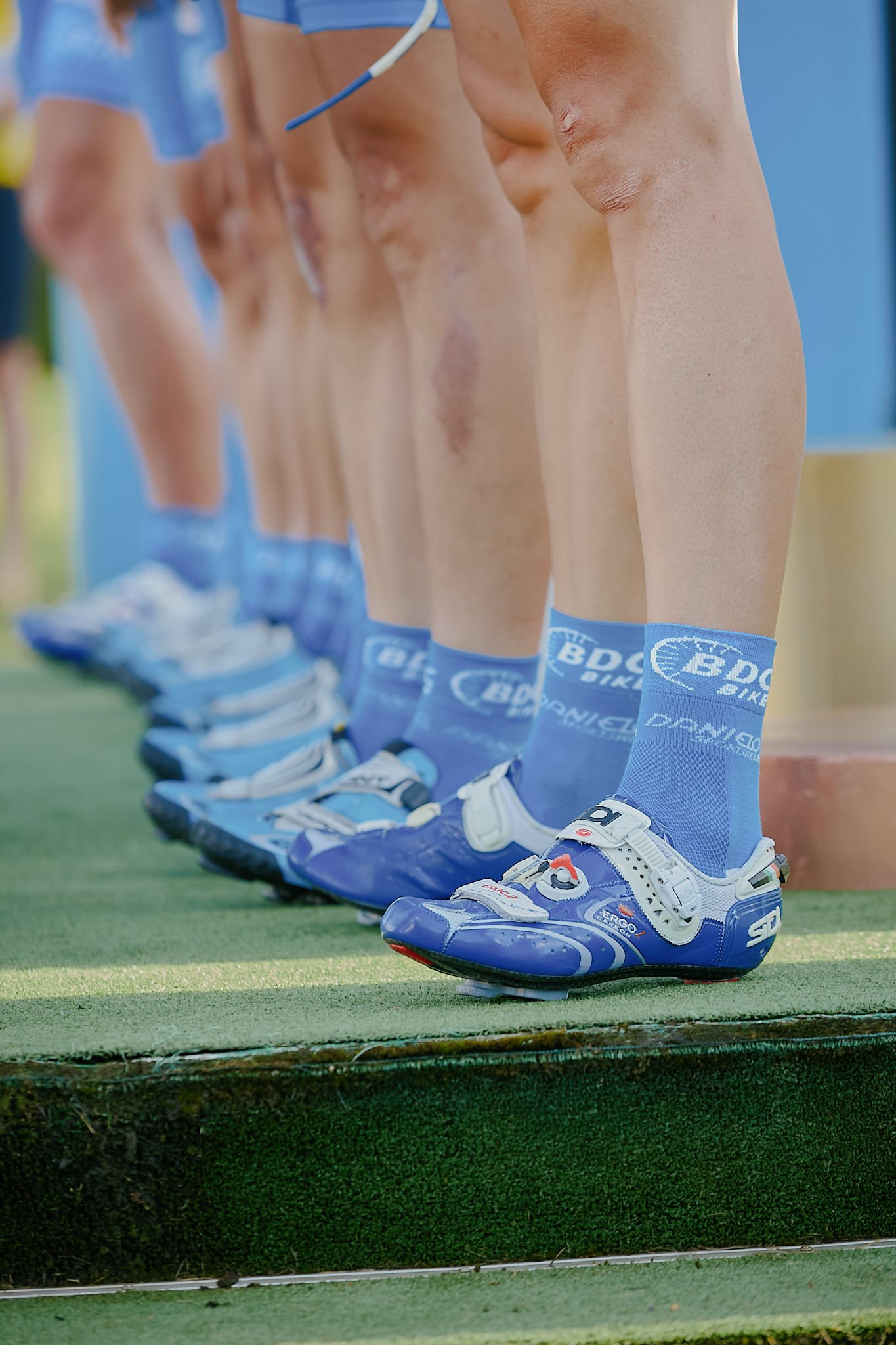 Line of hockey players standing on the ice in skates and blue socks with team logos, lining up in a sports arena.