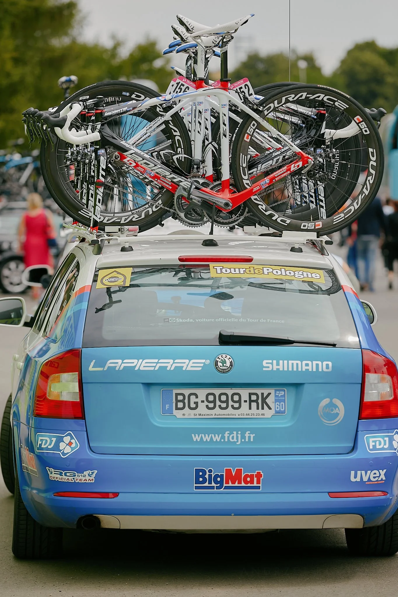 A support vehicle for a cycling race with five racing bicycles mounted on the roof, and various sponsor logos on the rear of the vehicle.
