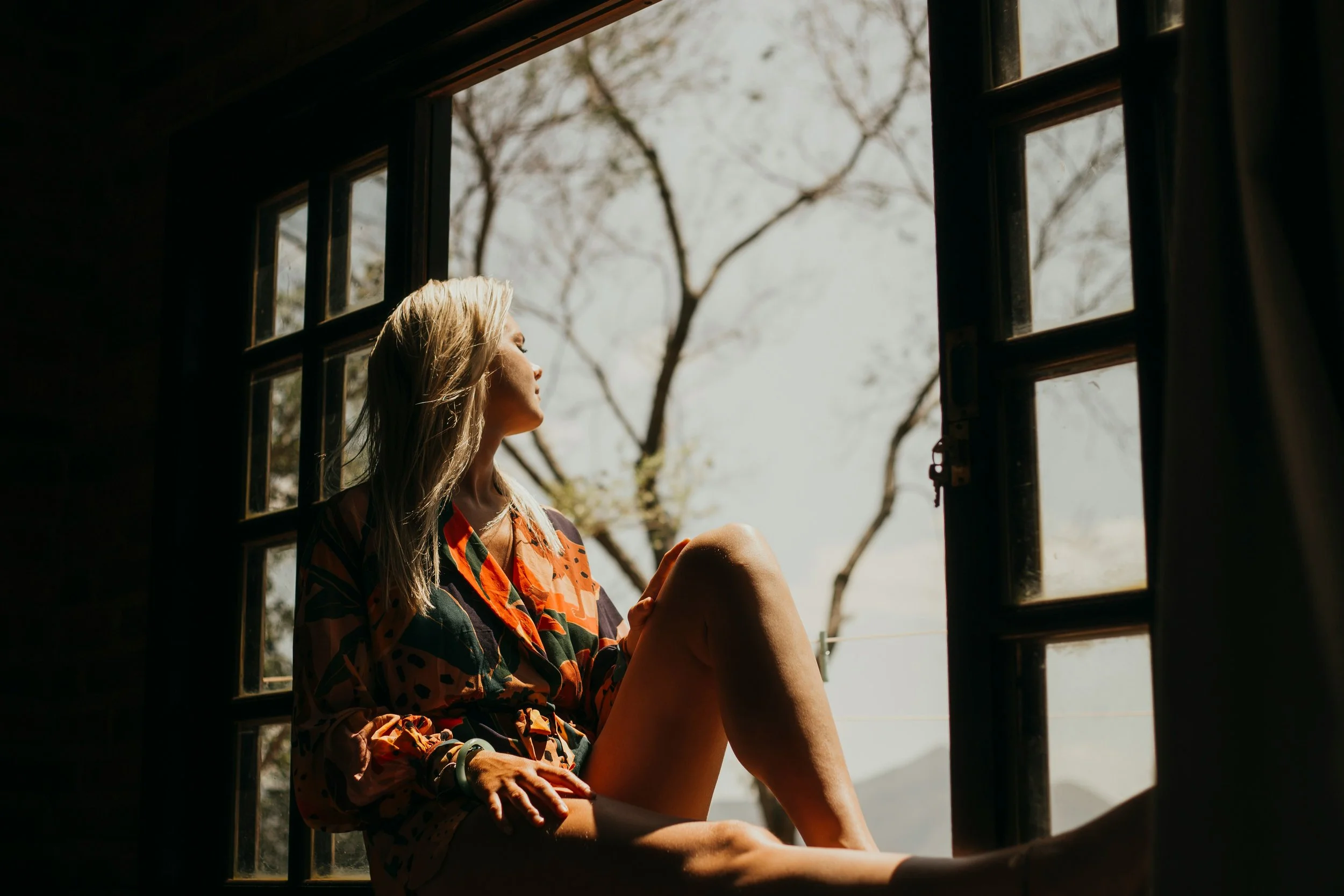 mujer rubia sentada viendo por una ventana