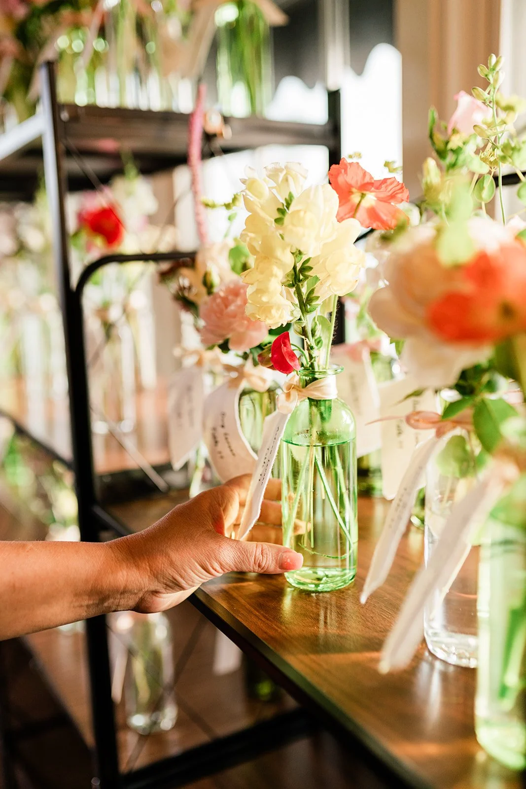 A feature guest seating chart of colorful bud vases welcomes guests to a wedding at North Shore House in Swartswood, NJ.