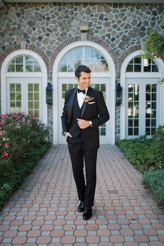 The groom before the Coach House stone arches