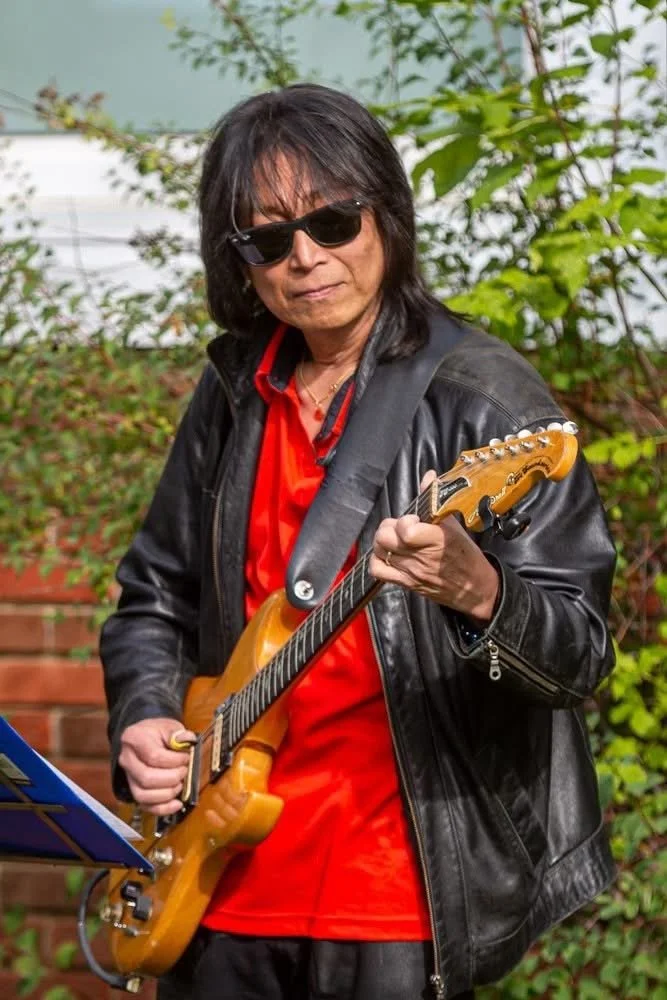 A nice photo of Ryu with his electric guitar performing at a recent community event. 2025.