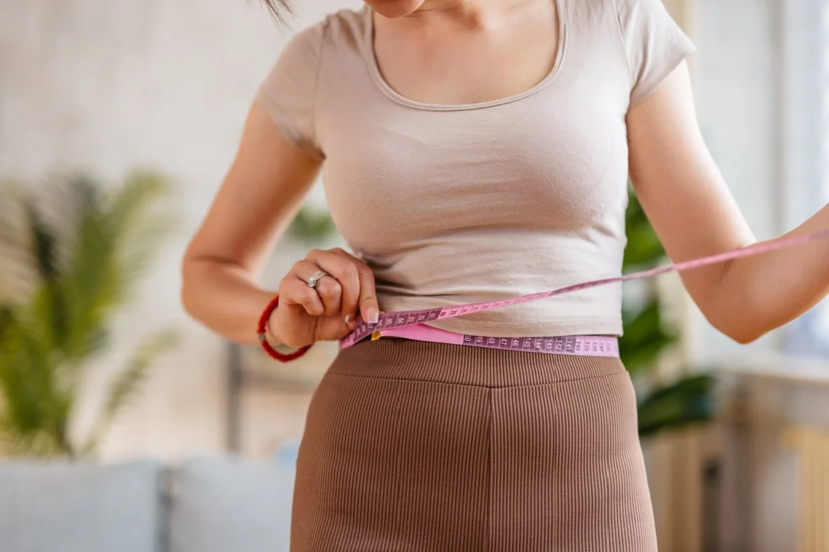 Woman measuring waist after weight loss with GLP-1 medications