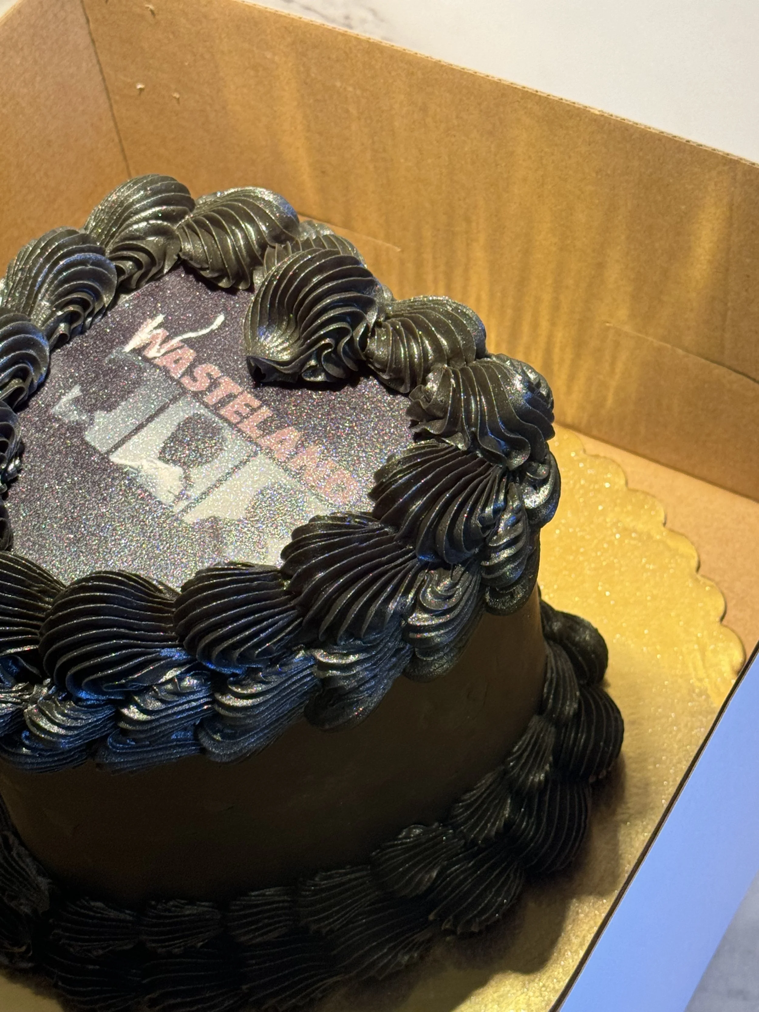 a birthday cake decorated with black frosting and glitter, with the 