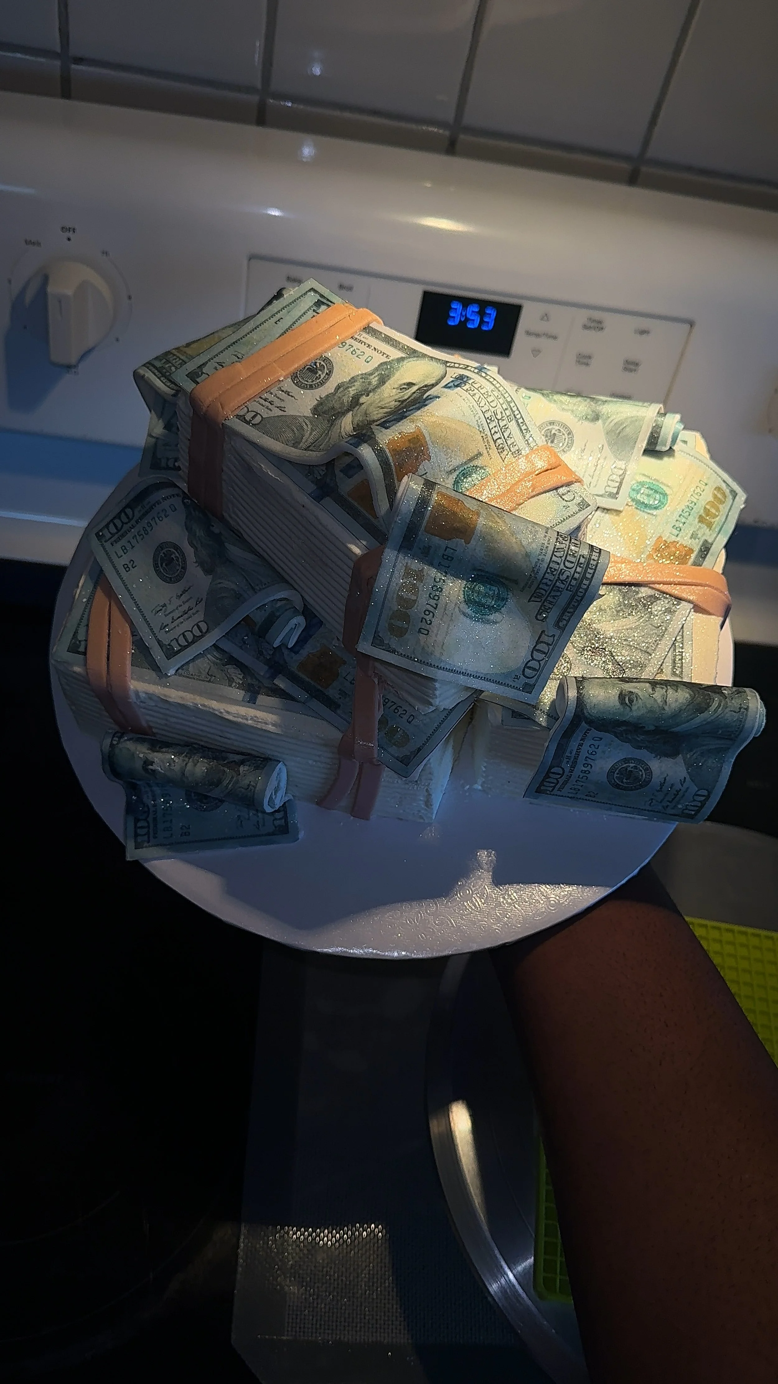 A cake decorated with numerous rolled and stacked US dollar bills on a white plate.