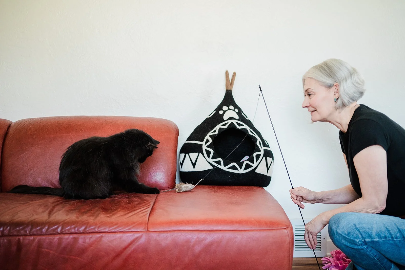 Photo of Sandra Grossmann, The Feline Consultant, playing with a cat with a cat feather toy.