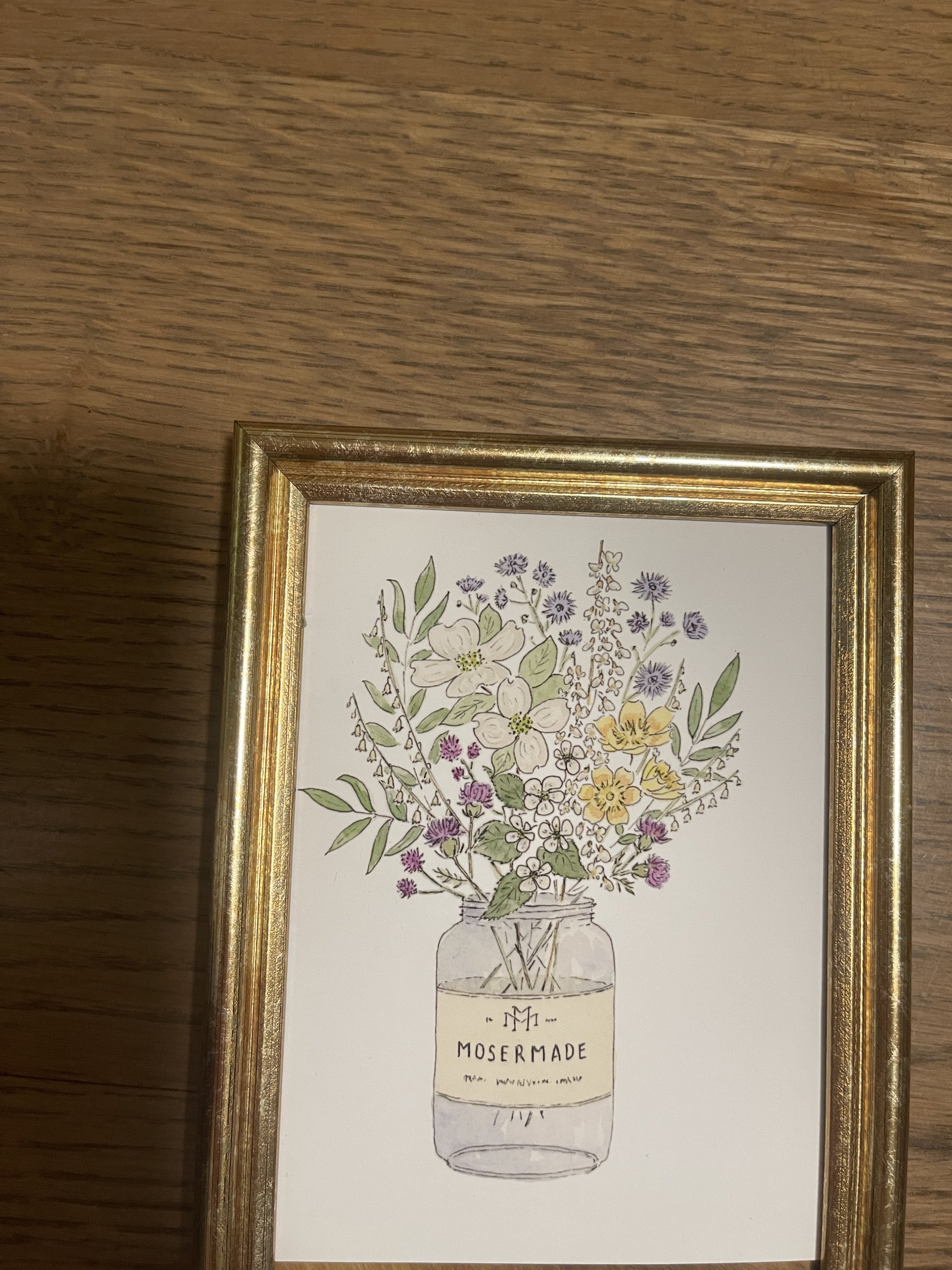 A framed watercolor artwork featuring colorful local Va wildflowers in a mosermade honey jar, highlighting the charm of nature.