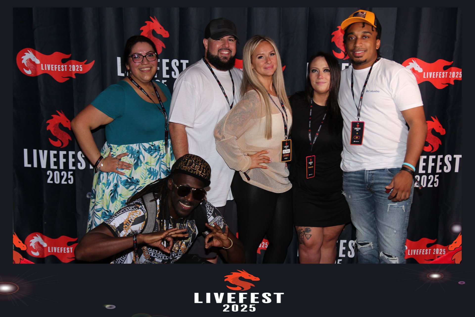A group of six diverse people posing together at LiveFest 2025, with red and black event banners in the background.