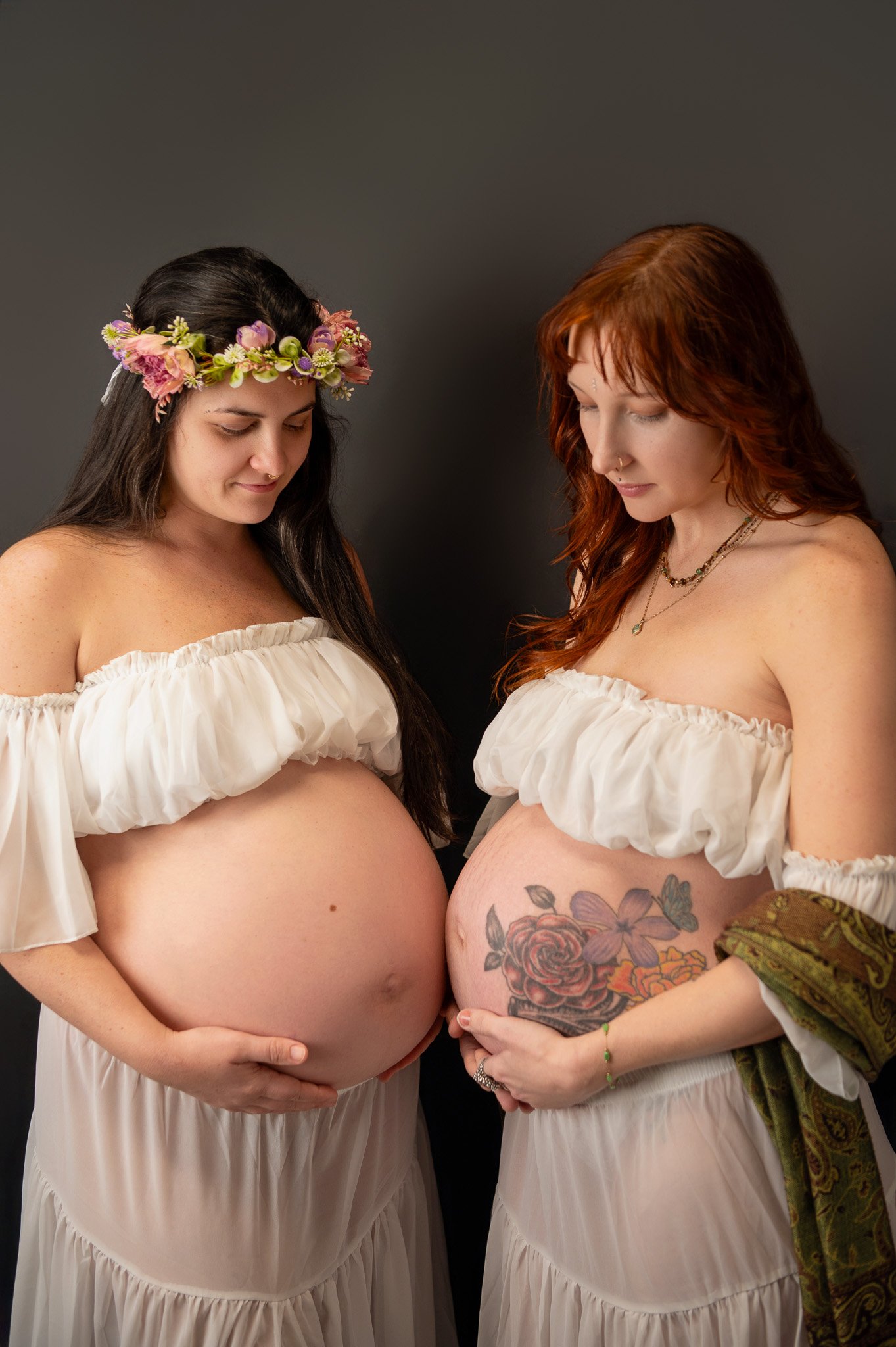 two pregnant women touching bare bellies