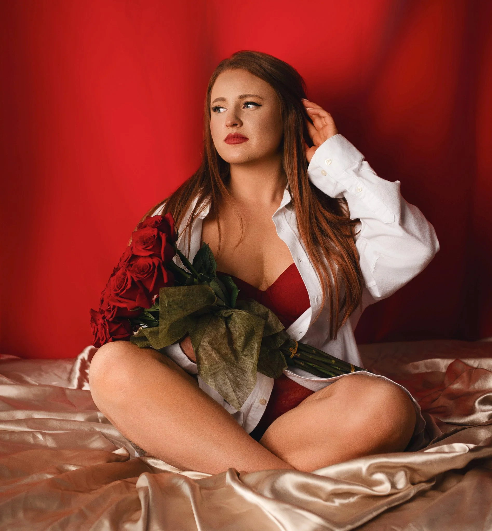 woman in red lingerie and white button down shirt sitting with red roses