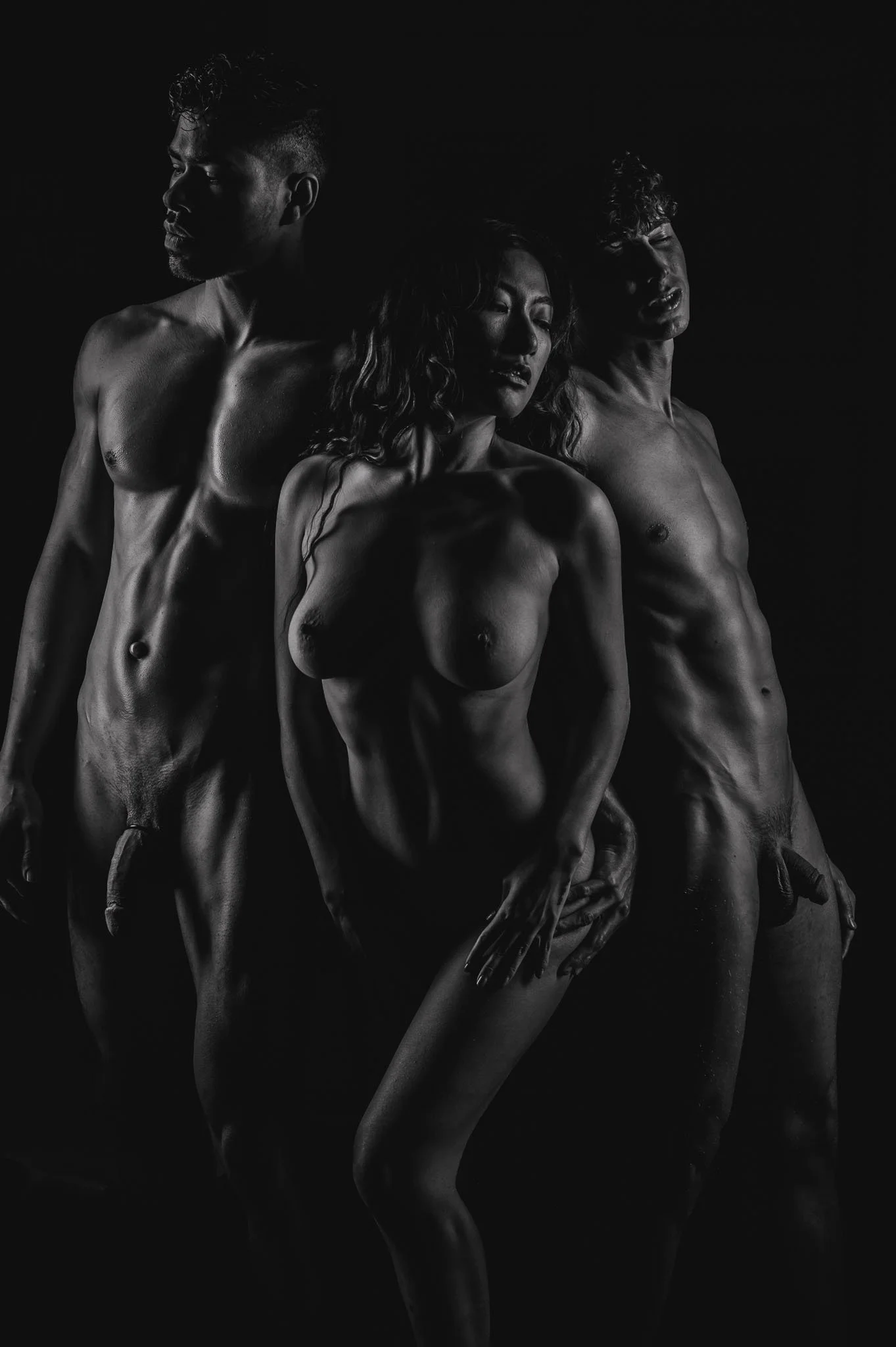 black and white image of two nude men and one nude woman standing in artful pose
