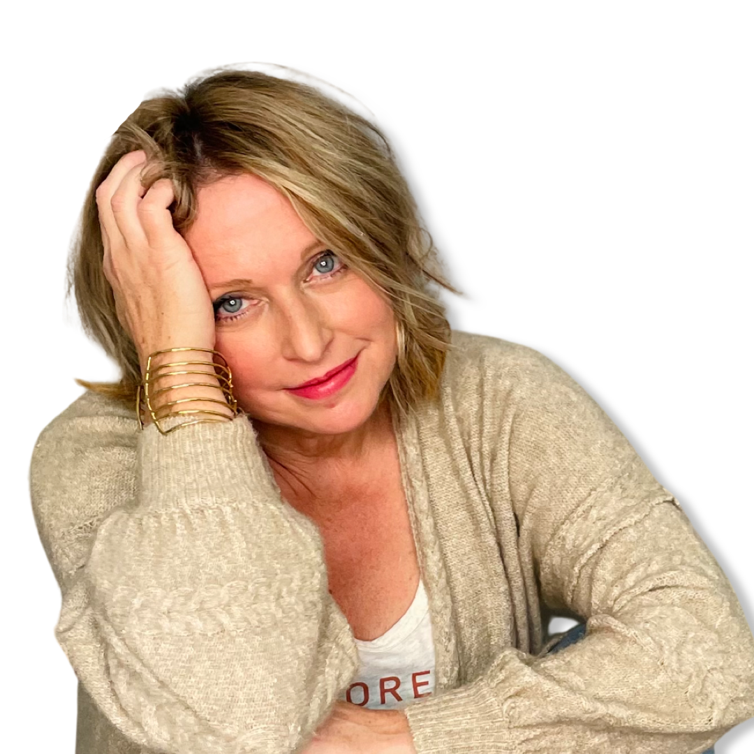A woman with blonde hair and blue eyes, wearing a beige sweater and gold bracelets, smiling slightly with her head resting on her hand, against a black background.