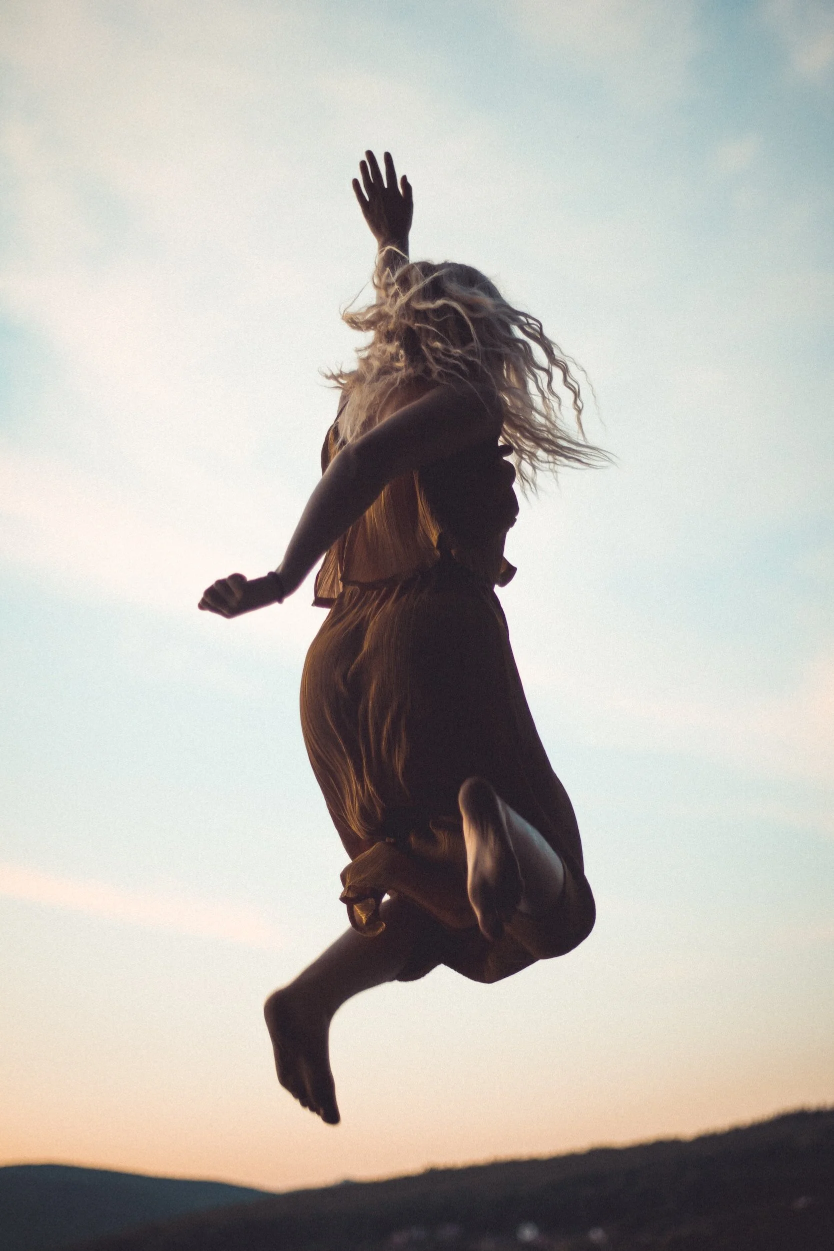 Person jumping outdoors against a sunset sky.