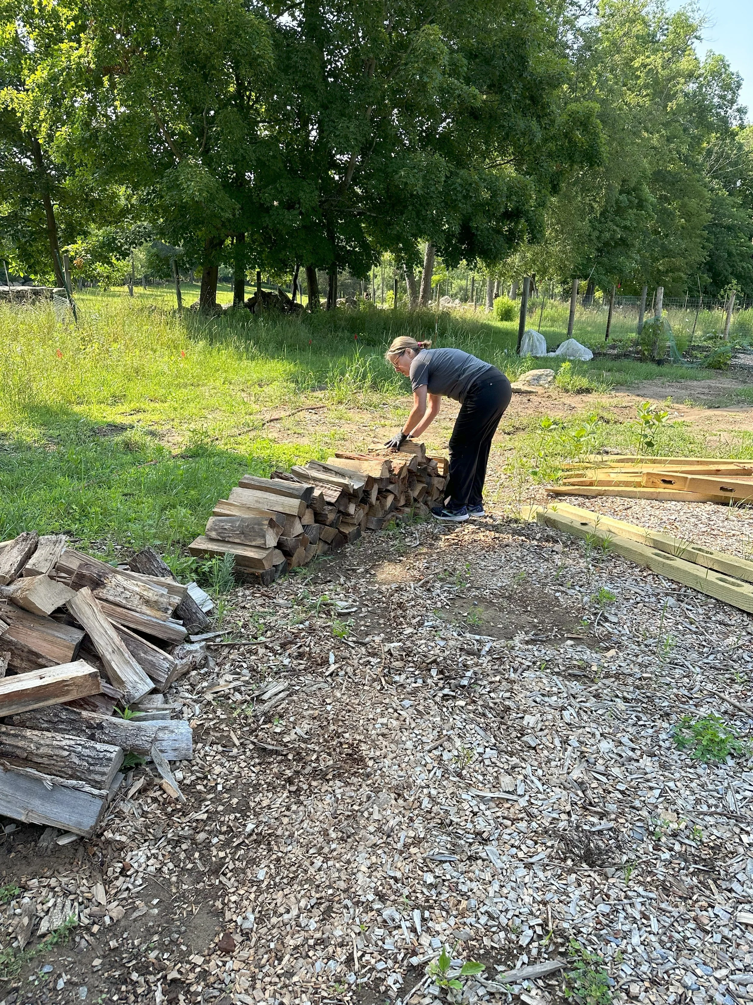 Refresh crew member laying out wood to make an organized wood pile.