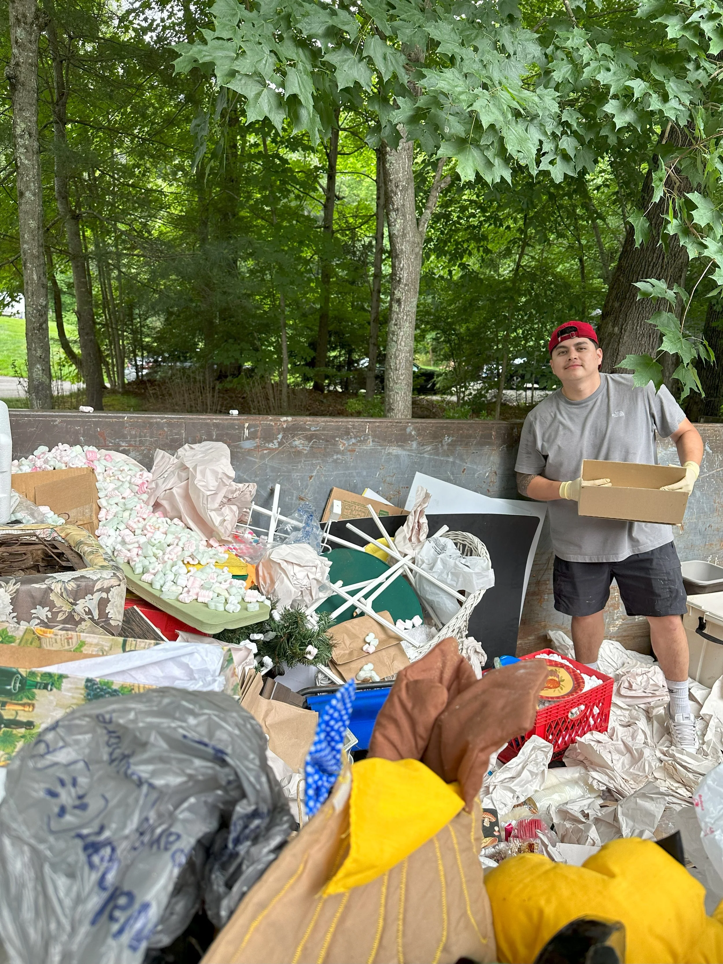 Refresh crew member, Lucas, organizing and putting trash in a dumpster at one of our hoarding job sites.