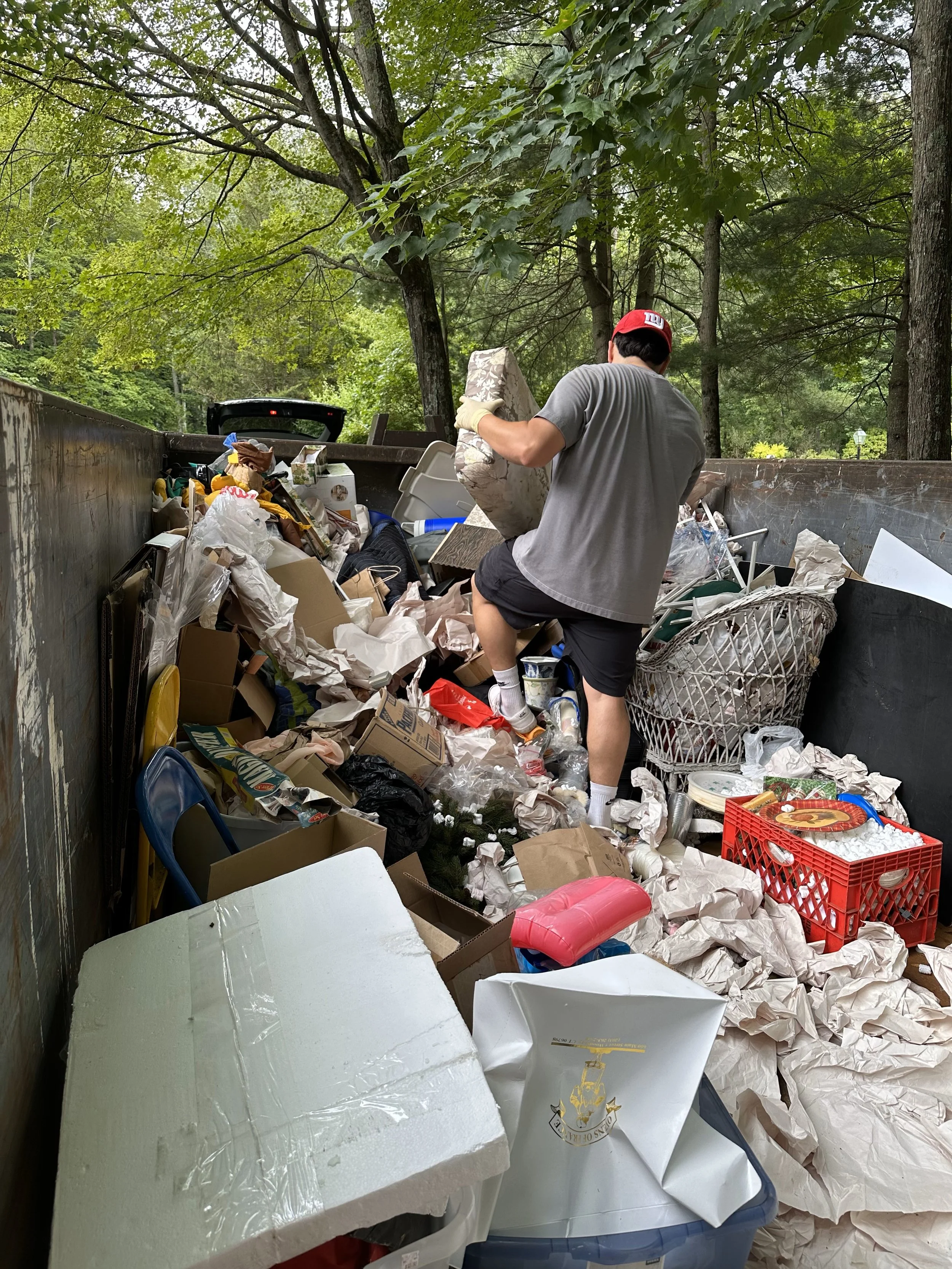 Refresh crew member in a dumpster organizing the trash to optimize space.